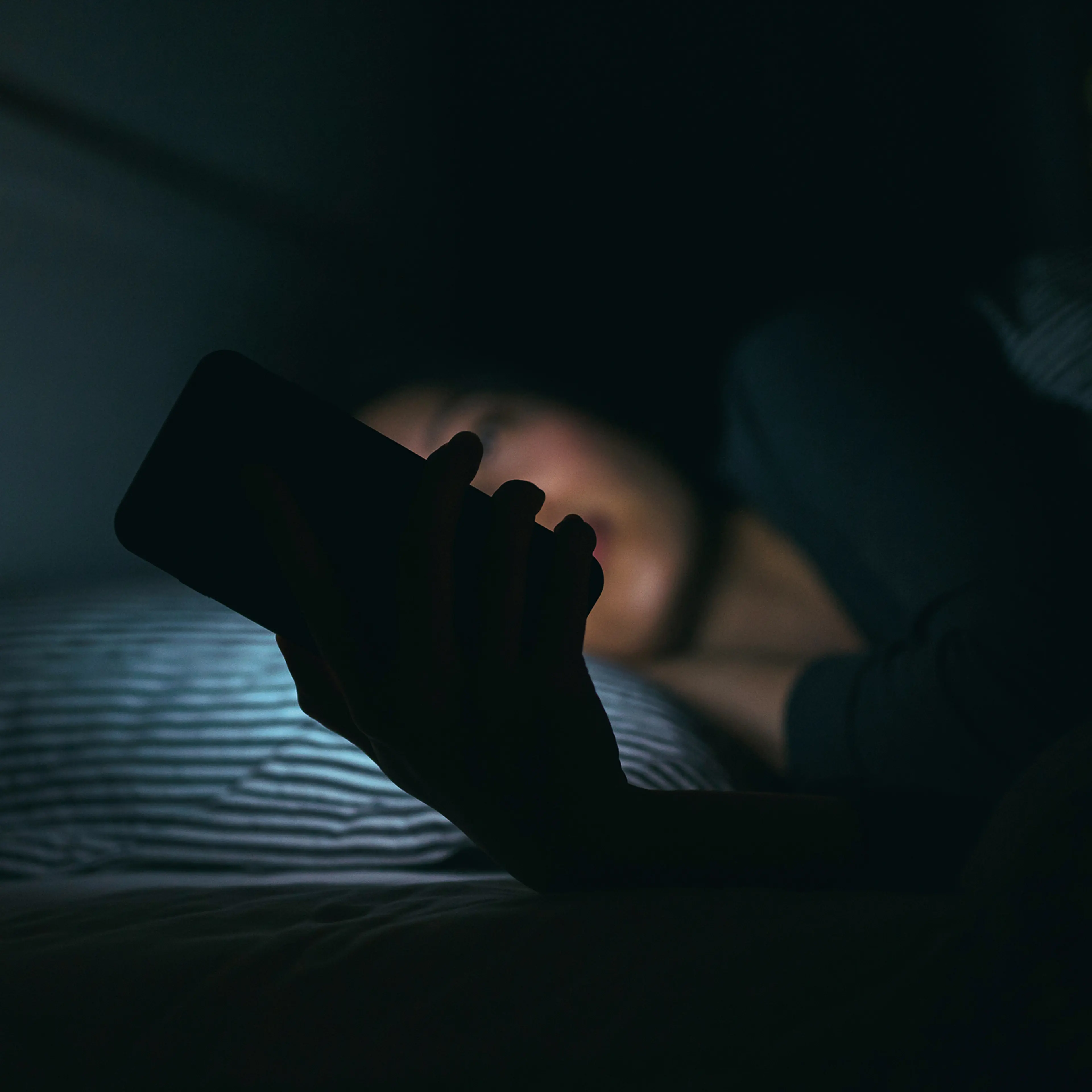 Young woman texting while lying in bed at night