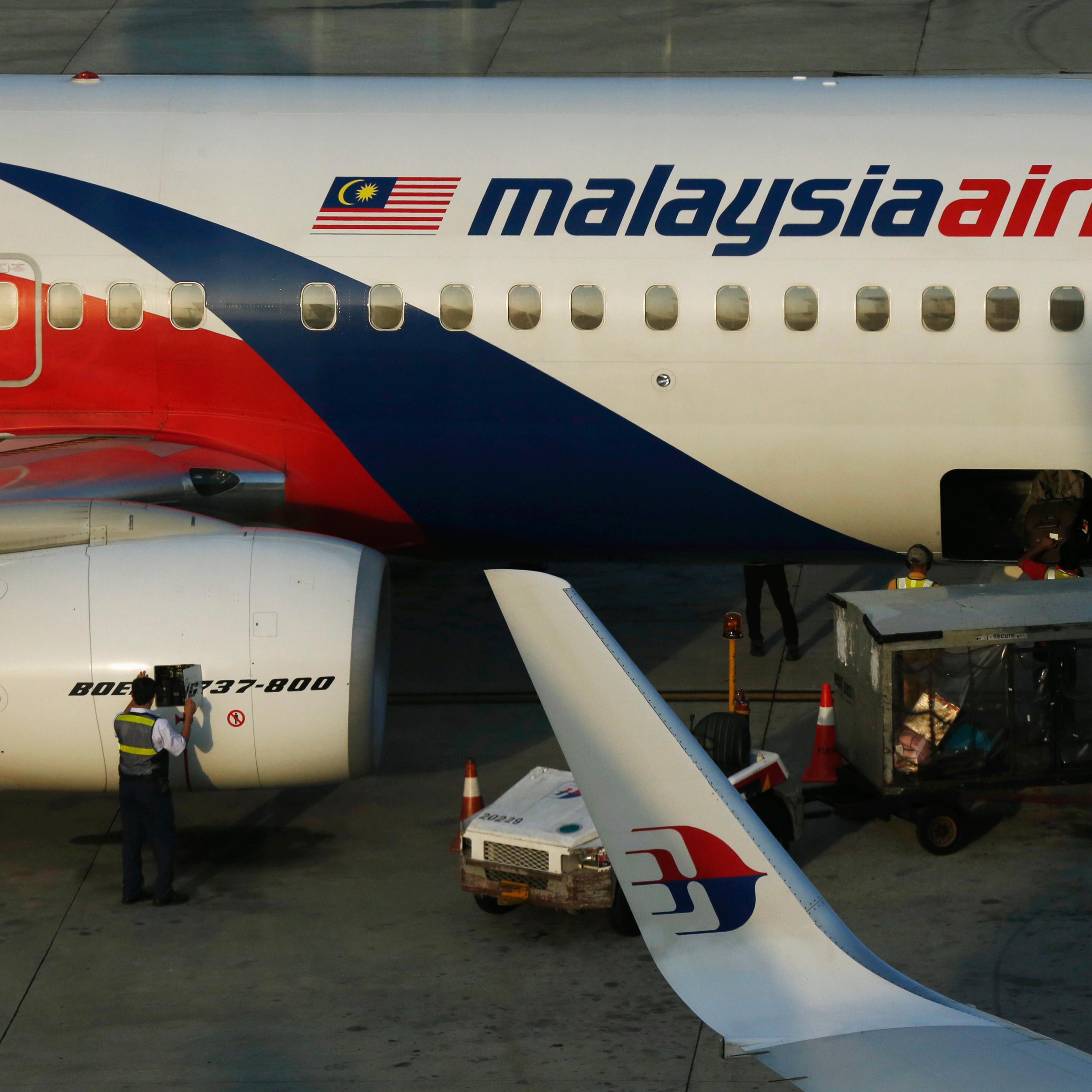 A member of ground crew works on a Malaysia Airlines Boeing 737-800 airplane on the runway at Kuala Lumpur International Airport in Sepang