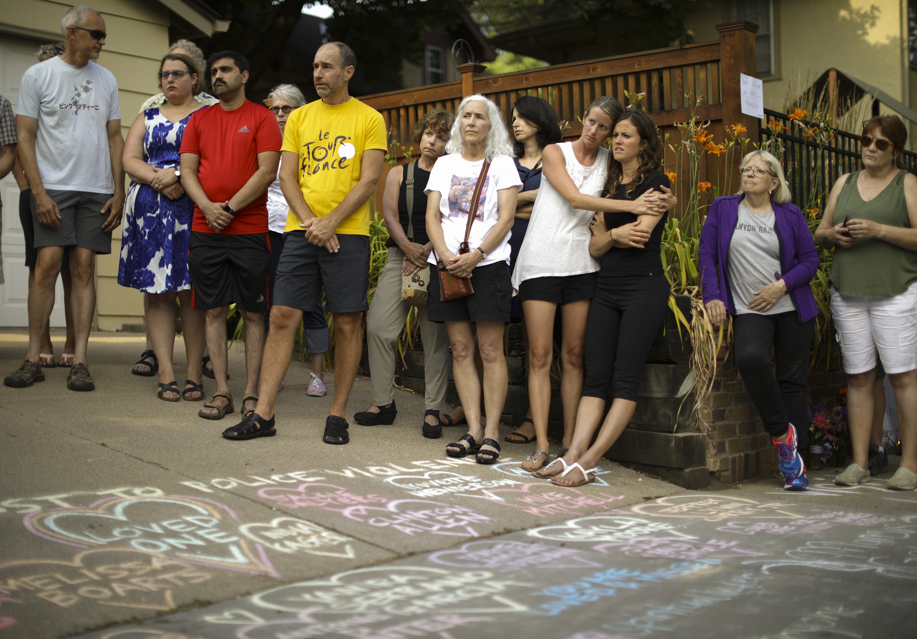 People listen as Bethany Bradley of Women's March Minnesota speaks at the beginning of a vigil to remember Justine Damond, from Sydney, Australia, who was shot and killed late Saturday by police, Sunday evening, July 16, 2017 in Minneapolis.