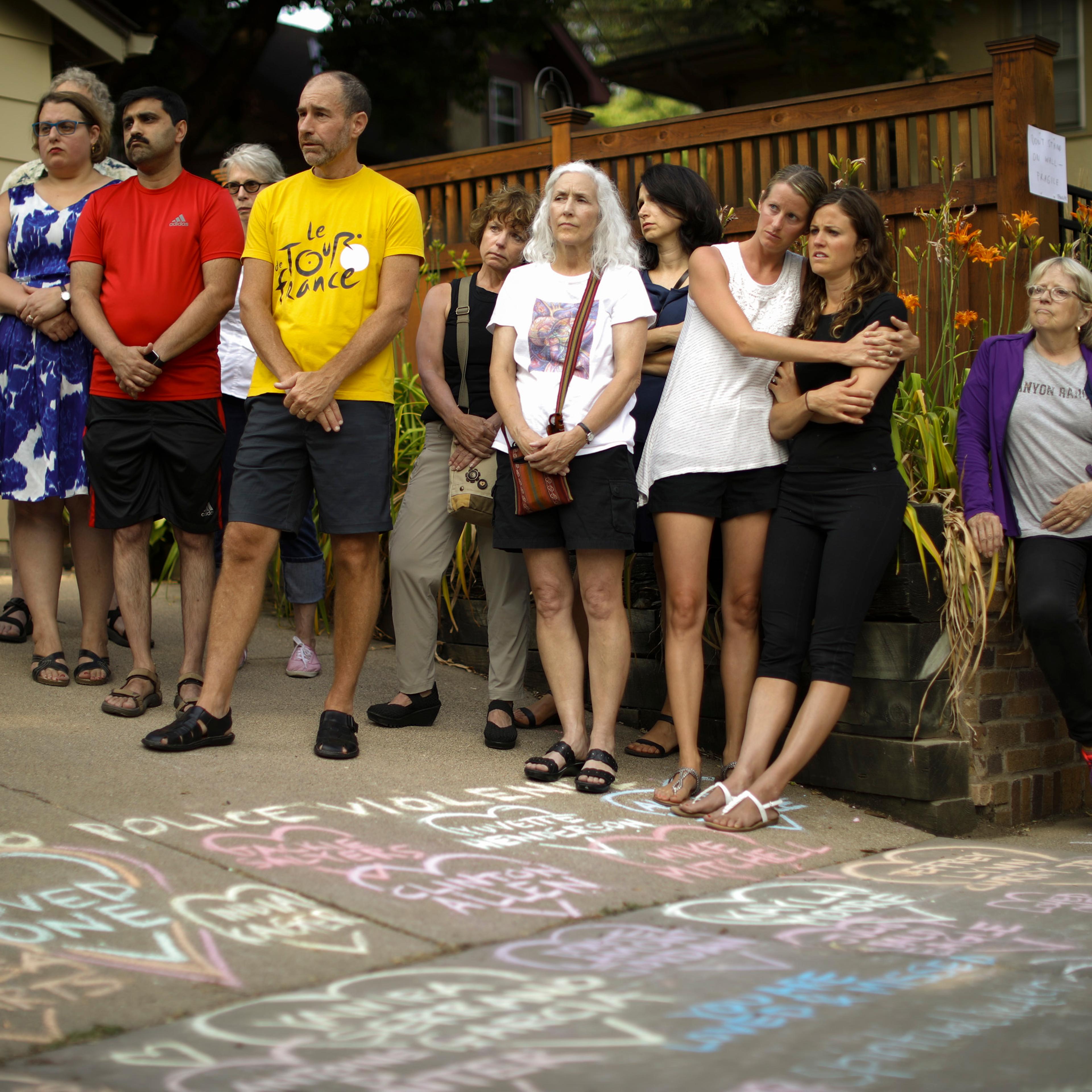 People listen as Bethany Bradley of Women's March Minnesota speaks at the beginning of a vigil to remember Justine Damond, from Sydney, Australia, who was shot and killed late Saturday by police, Sunday evening, July 16, 2017 in Minneapolis.