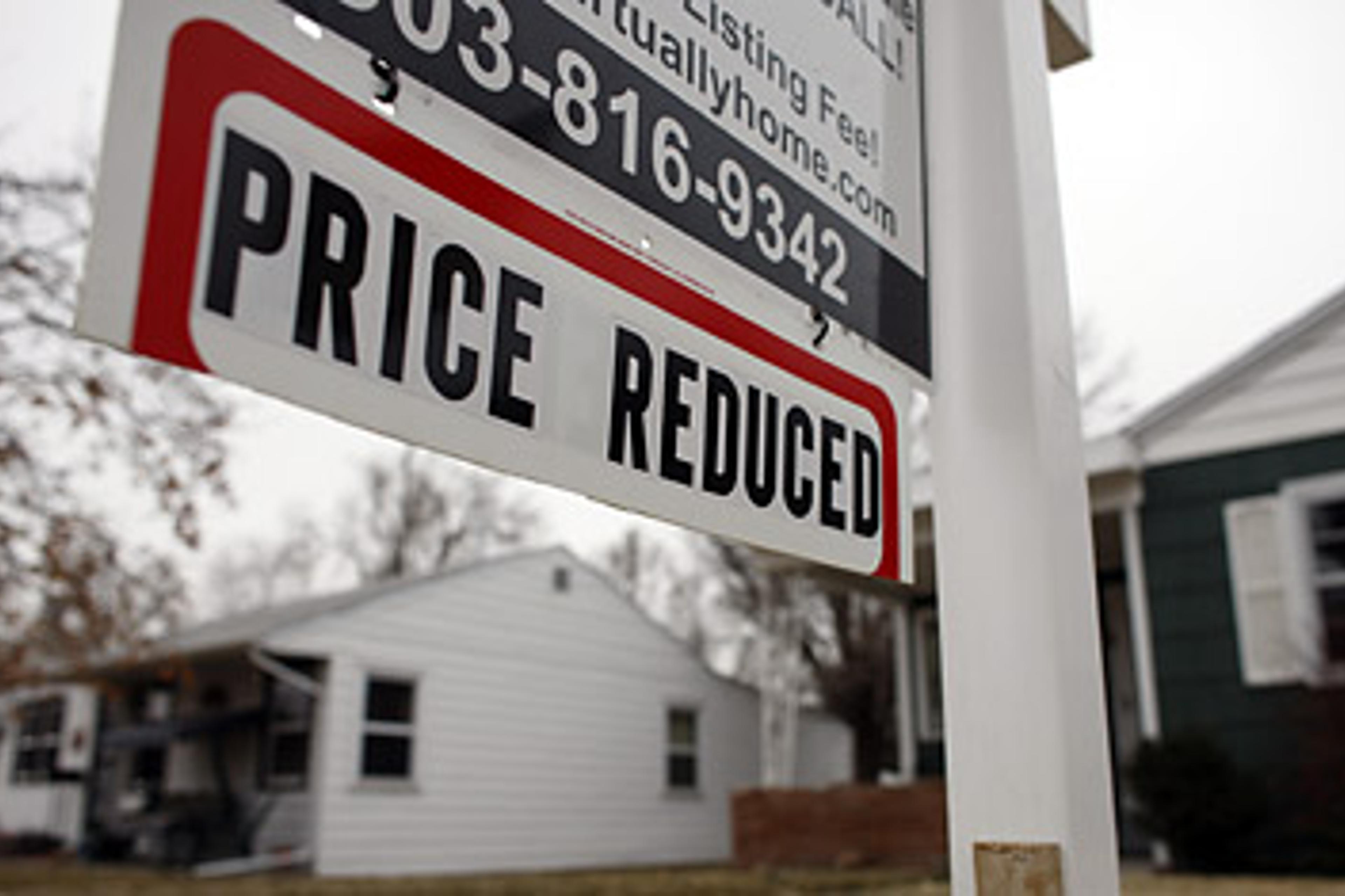 A price reduced placard hangs below the sale sign outside an existing home on the market in the south Denver suburb of Englewood, Colo