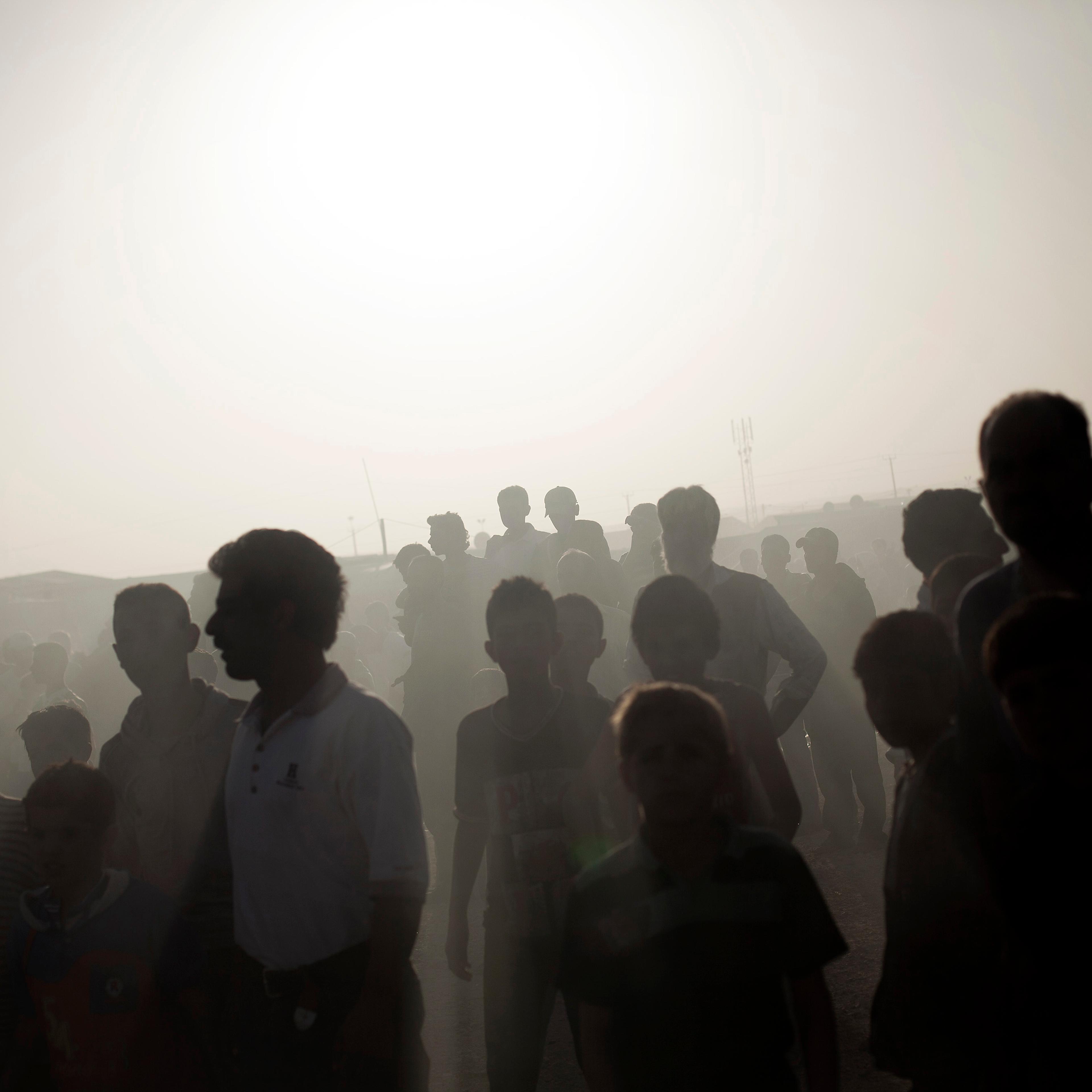 Dozens of Syrian refugees watch a tent and a trailer on fire at the Zaatari Refugee camp near the Syrian border in Jordan, Oct. 22, 2013.