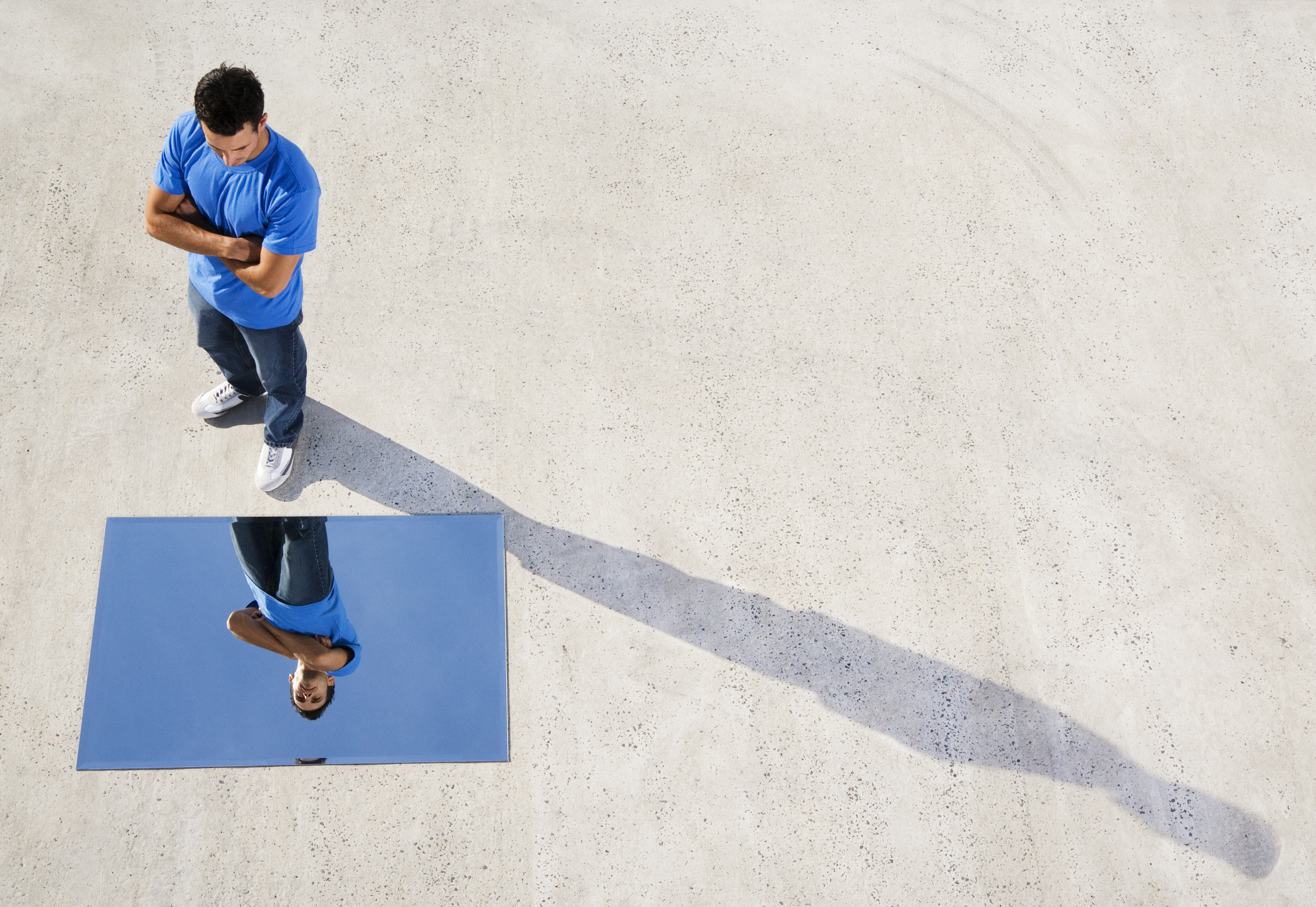 Man standing with mirror on ground and reflection