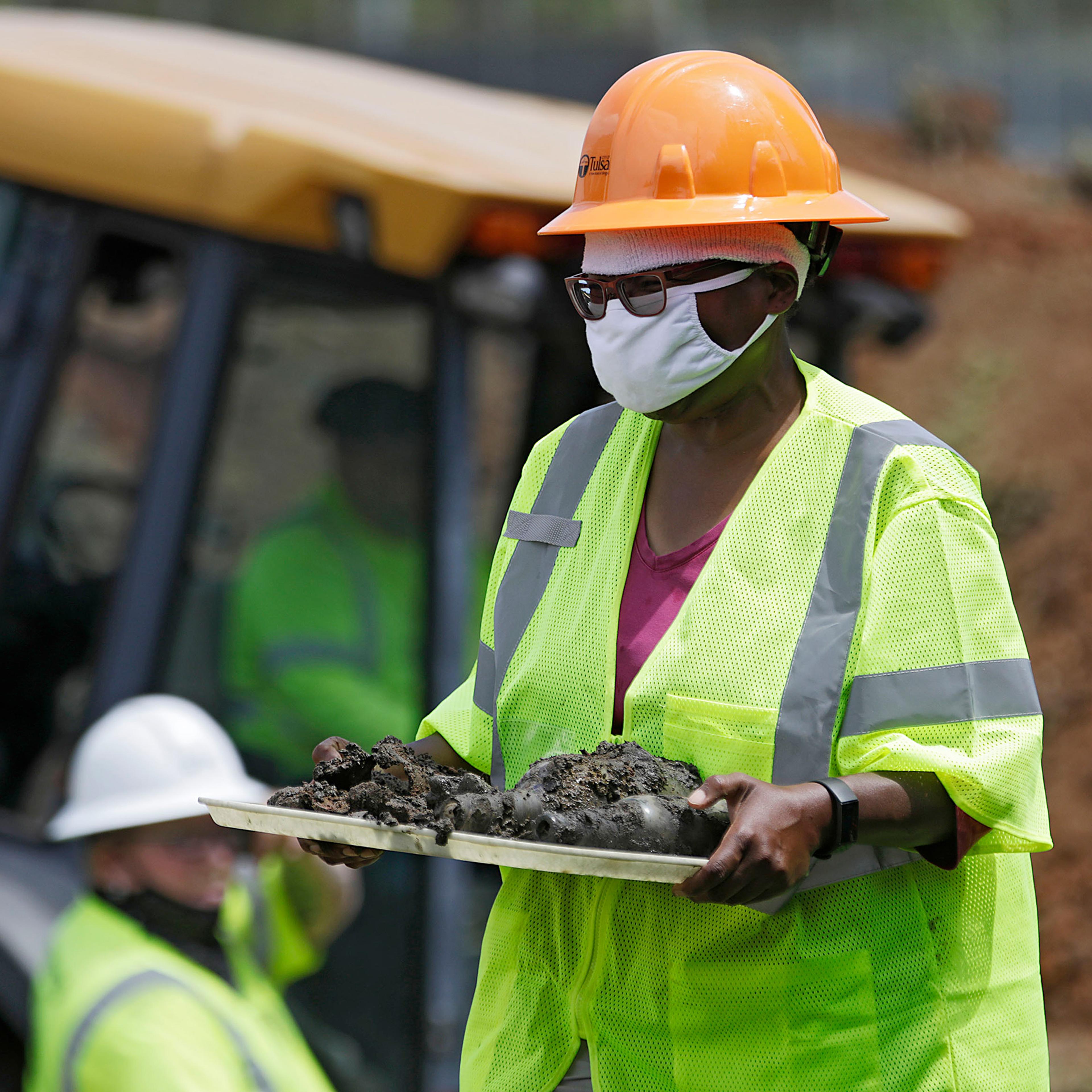 Forensic anthropologist Phoebe Stubblefield carries a tray of items found at Oaklawn Cemetery during a test excavation in the search for possible mass graves from the 1921 Tulsa Race Massacre in Tulsa, Okla on July 21, 2020.