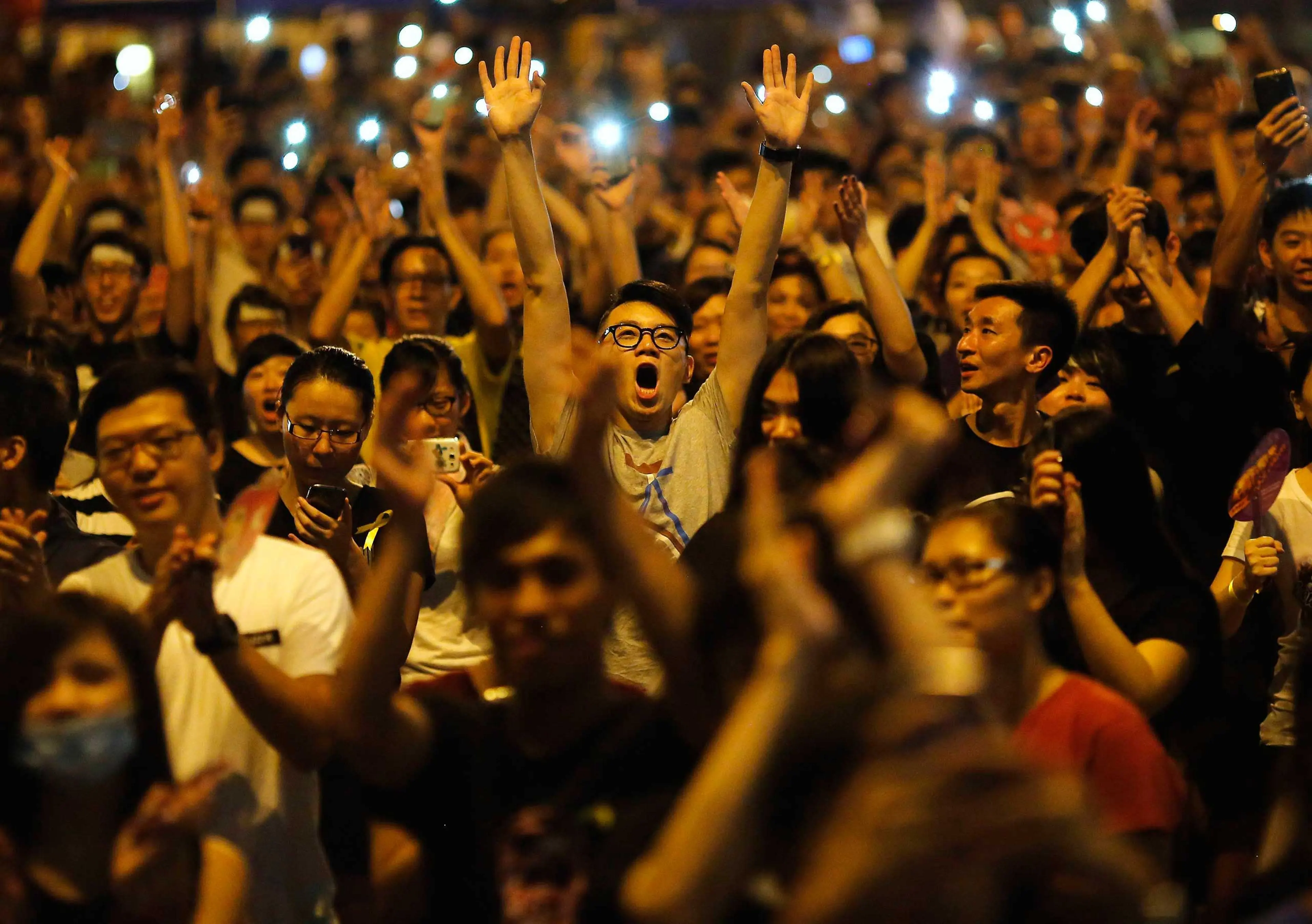 Protesters react as Joshua Wong (not pictured), leader of the student movement, speaks to the crowd outside the government headquarters building in Hong Kong, Oct.1, 2014.