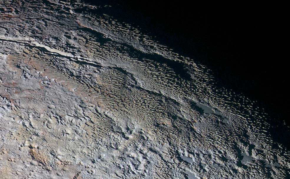 In this extended color image of Pluto taken by NASA’s New Horizons spacecraft, rounded and bizarrely textured mountains, informally named the Tartarus Dorsa, rise up along Pluto’s day-night terminator and show intricate but puzzling patterns of blue-gray ridges and reddish material in between. This view, roughly 330 miles (530 kilometers) across, combines blue, red and infrared images taken by the Ralph/Multispectral Visual Imaging Camera (MVIC) on July 14, 2015, and resolves details and colors on scales as small as 0.8 miles (1.3 kilometers).