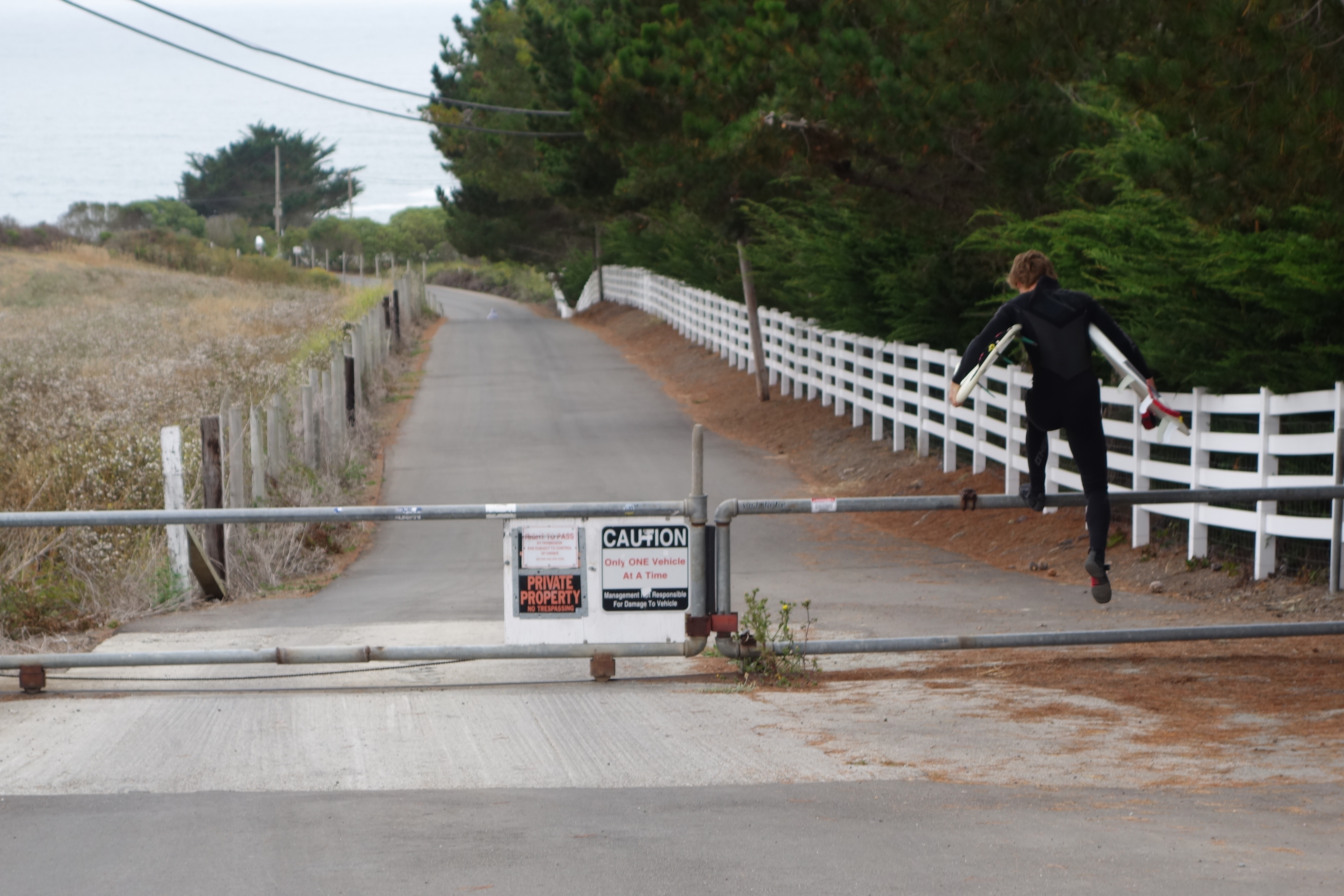 A surfer hops the gate at the top of Martins Beach Road, crossing property owned by venture capitalist Vinod Khosla in order to get to Martins Beach on August 7, 2014. 