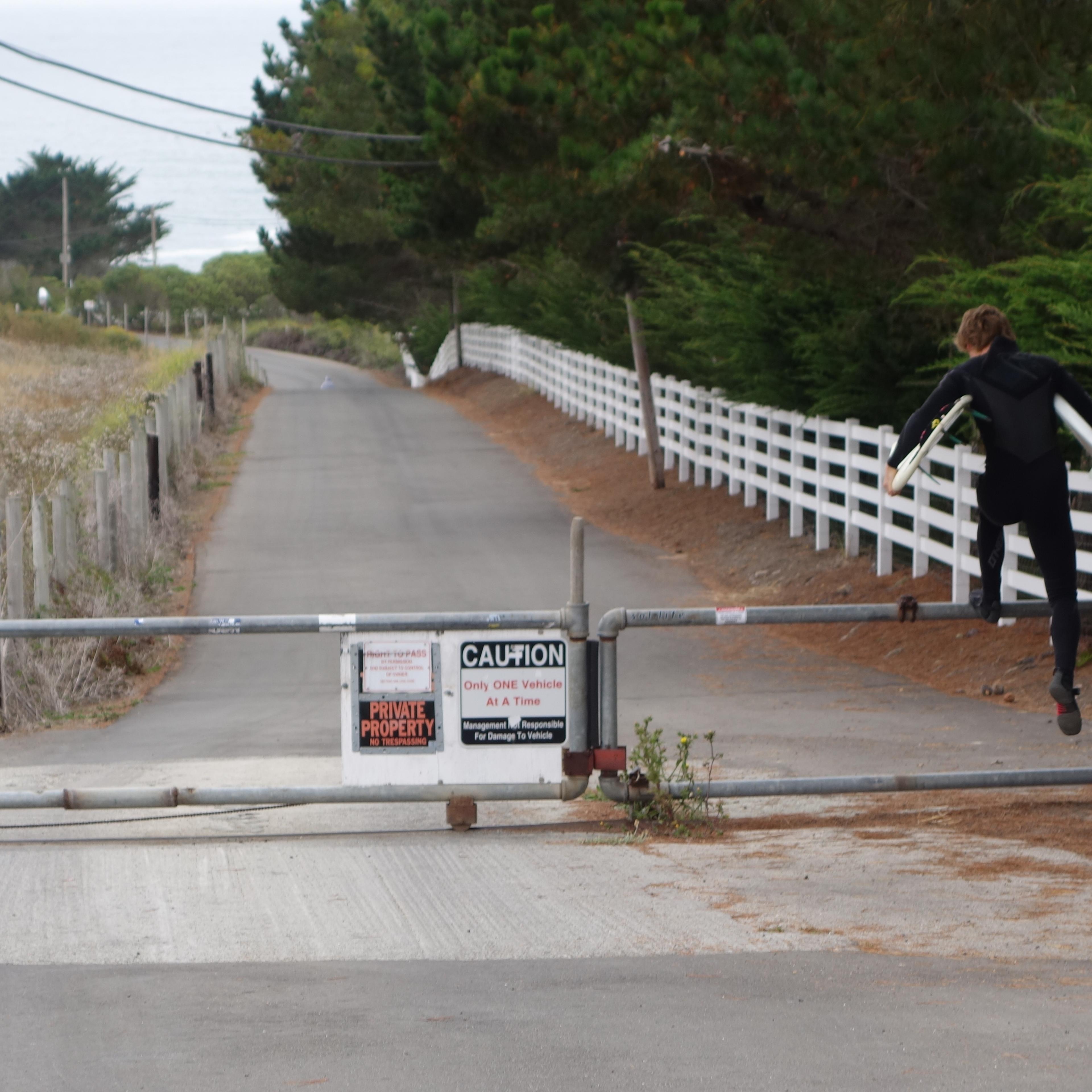 A surfer hops the gate at the top of Martins Beach Road, crossing property owned by venture capitalist Vinod Khosla in order to get to Martins Beach on August 7, 2014.