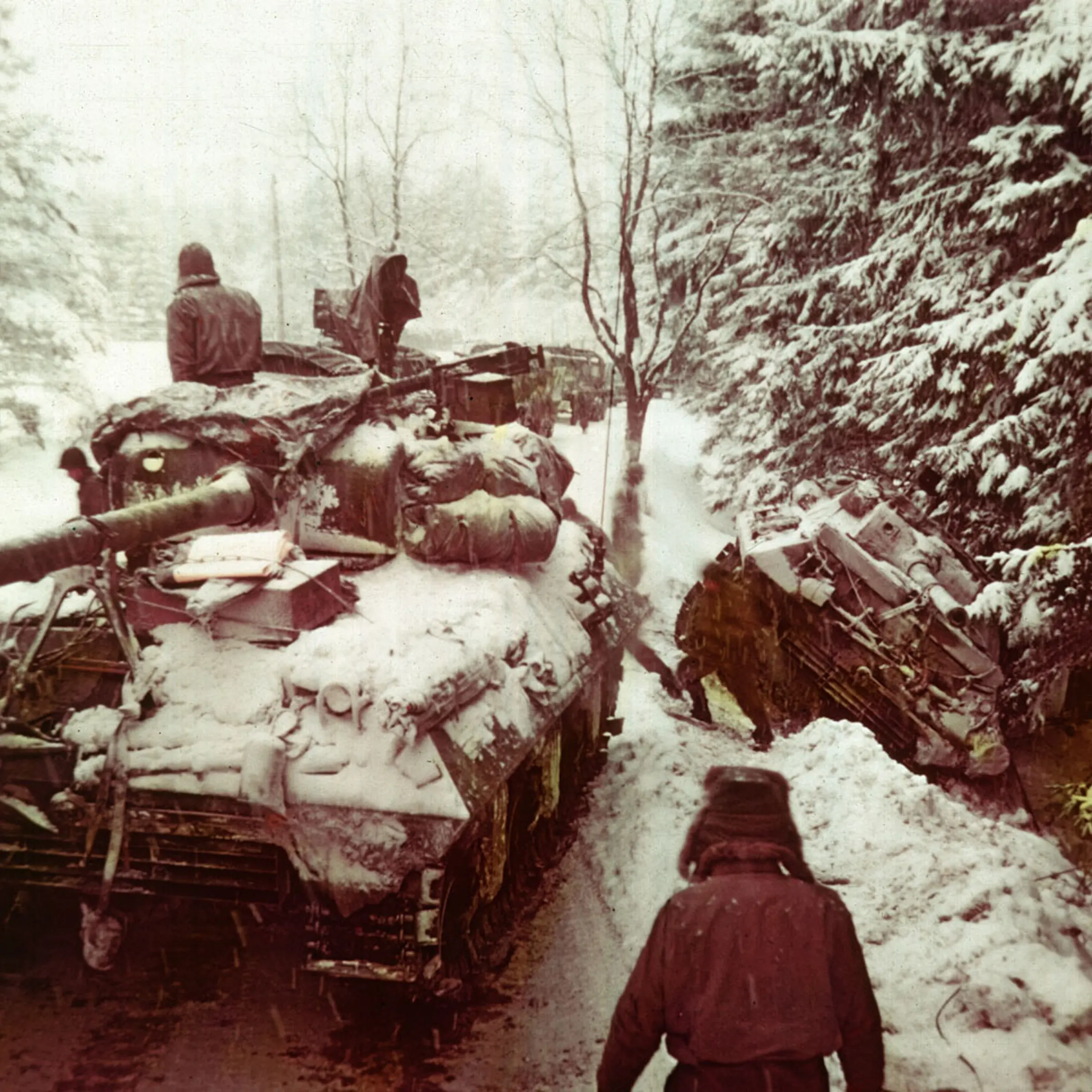 An American tank moves past another gun carriage which slid off an icy road in the Ardennes Forest during the Battle of the Bulge, Dec. 20, 1944.