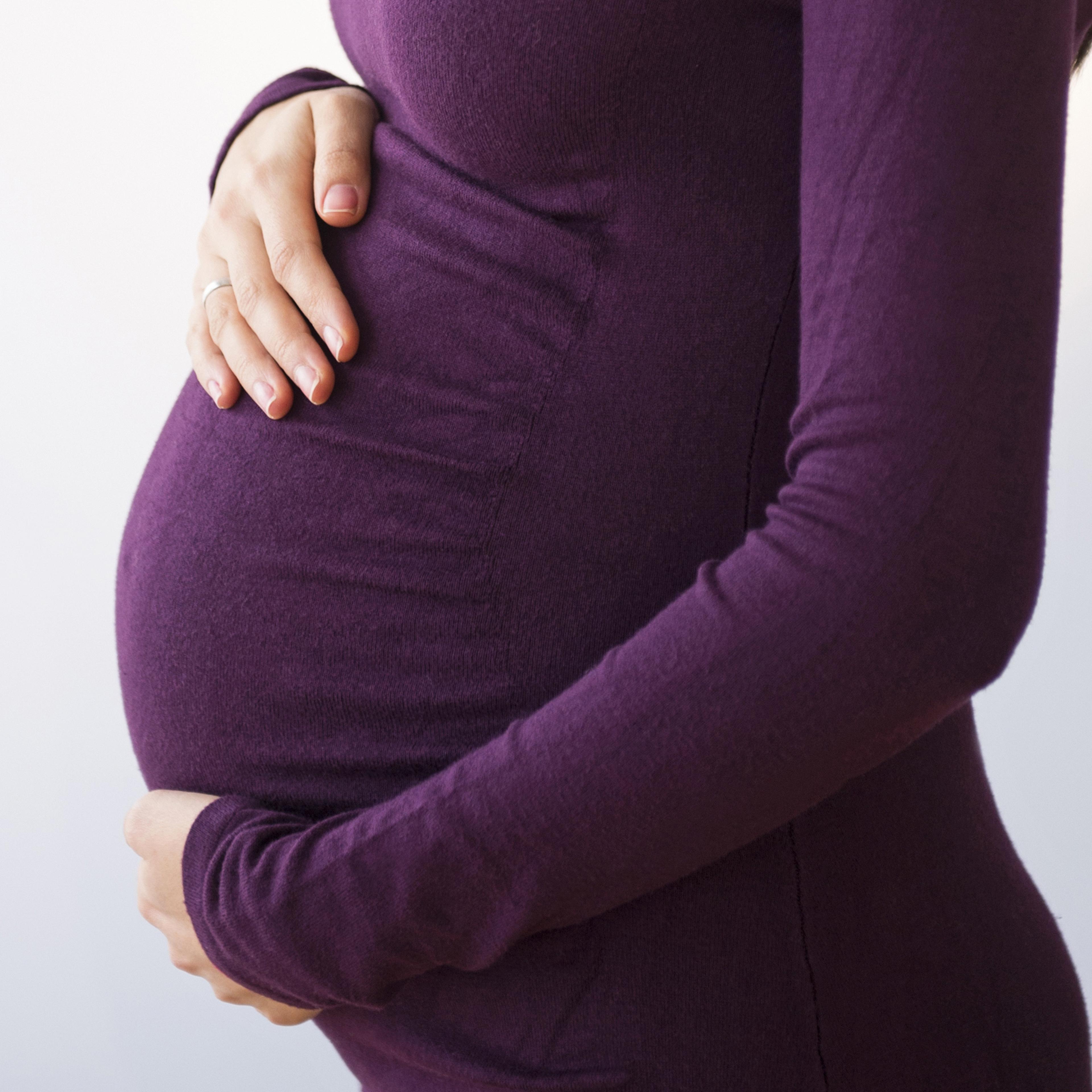 Pregnant Caucasian woman holding stomach