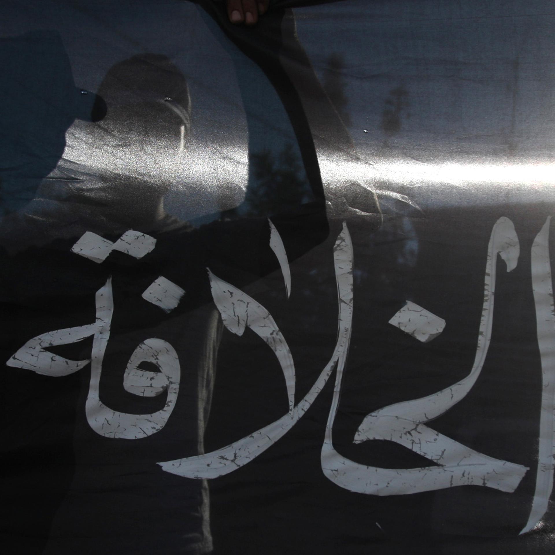 Silhouetted behind the Arabic word "cali