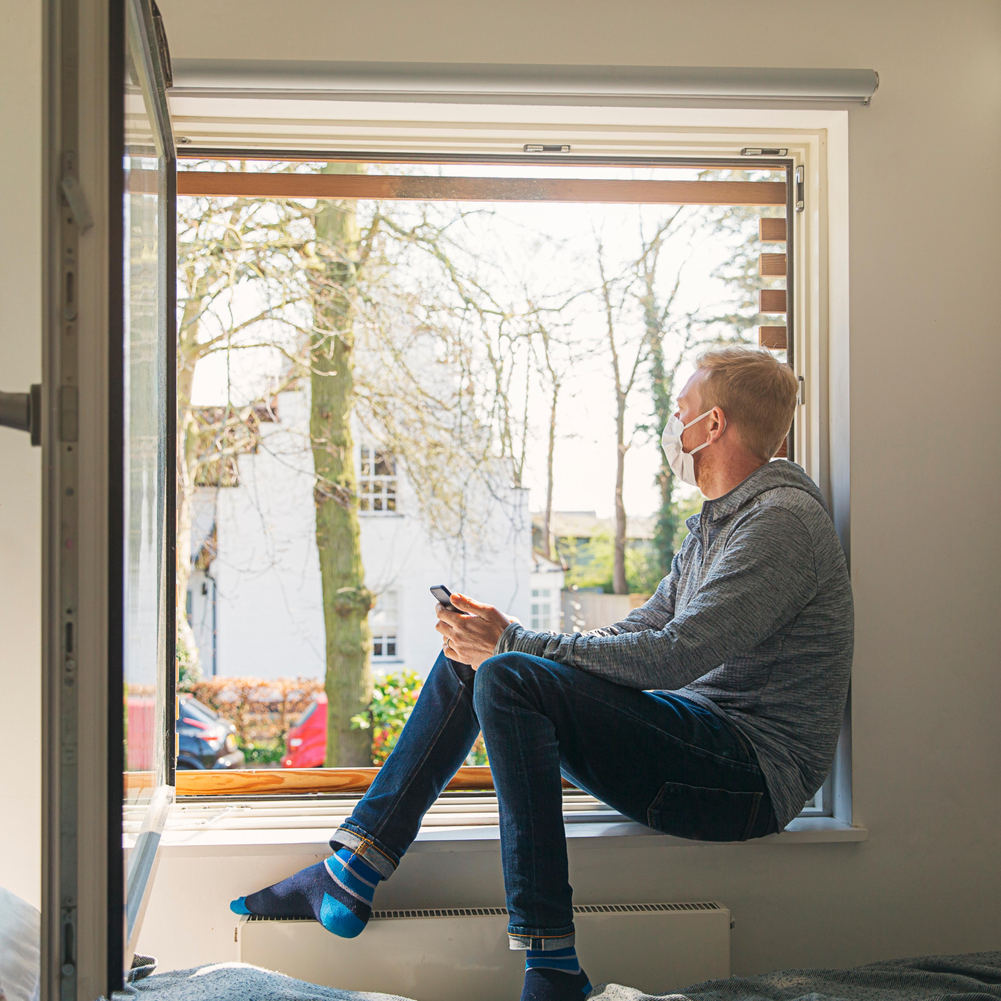 Man with mask looking out of window