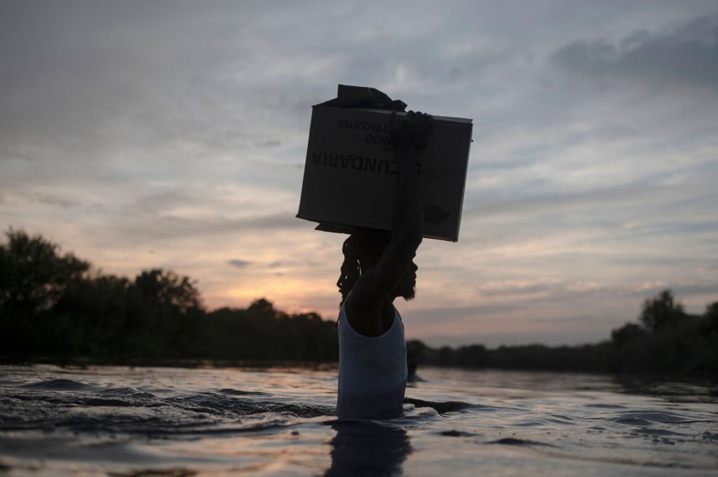 A Haitian migrant carries a box on his head as he crosses the Rio Grande River at the U.S.-Mexican border.