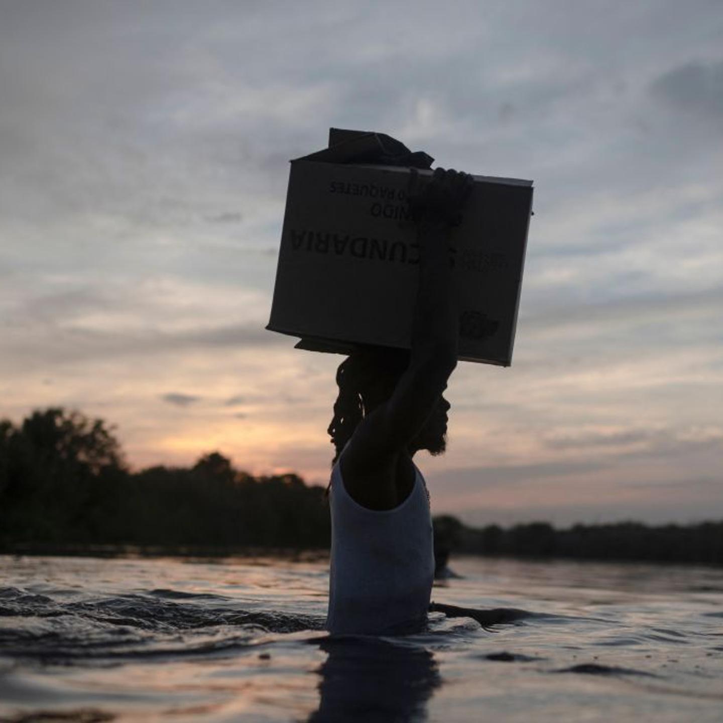 A Haitian migrant carries a box on his head as he crosses the Rio Grande River at the U.S.-Mexican border.