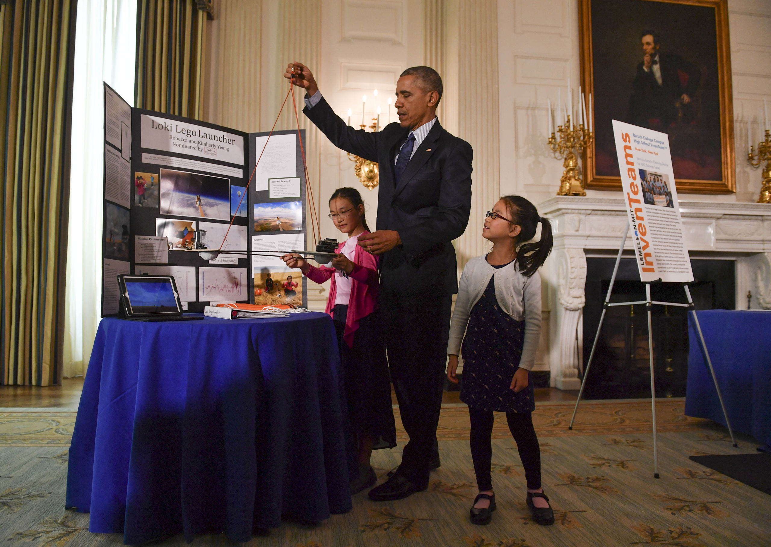 Sisters Kimberly, 9, right, and Rebecca Yeung, 11, of Seattle, WA., look on as President Barack Obama lifts their spacecraft science fair project during the sixth and final, annual White House Science Fair at The White House in Washington on April 13, 20