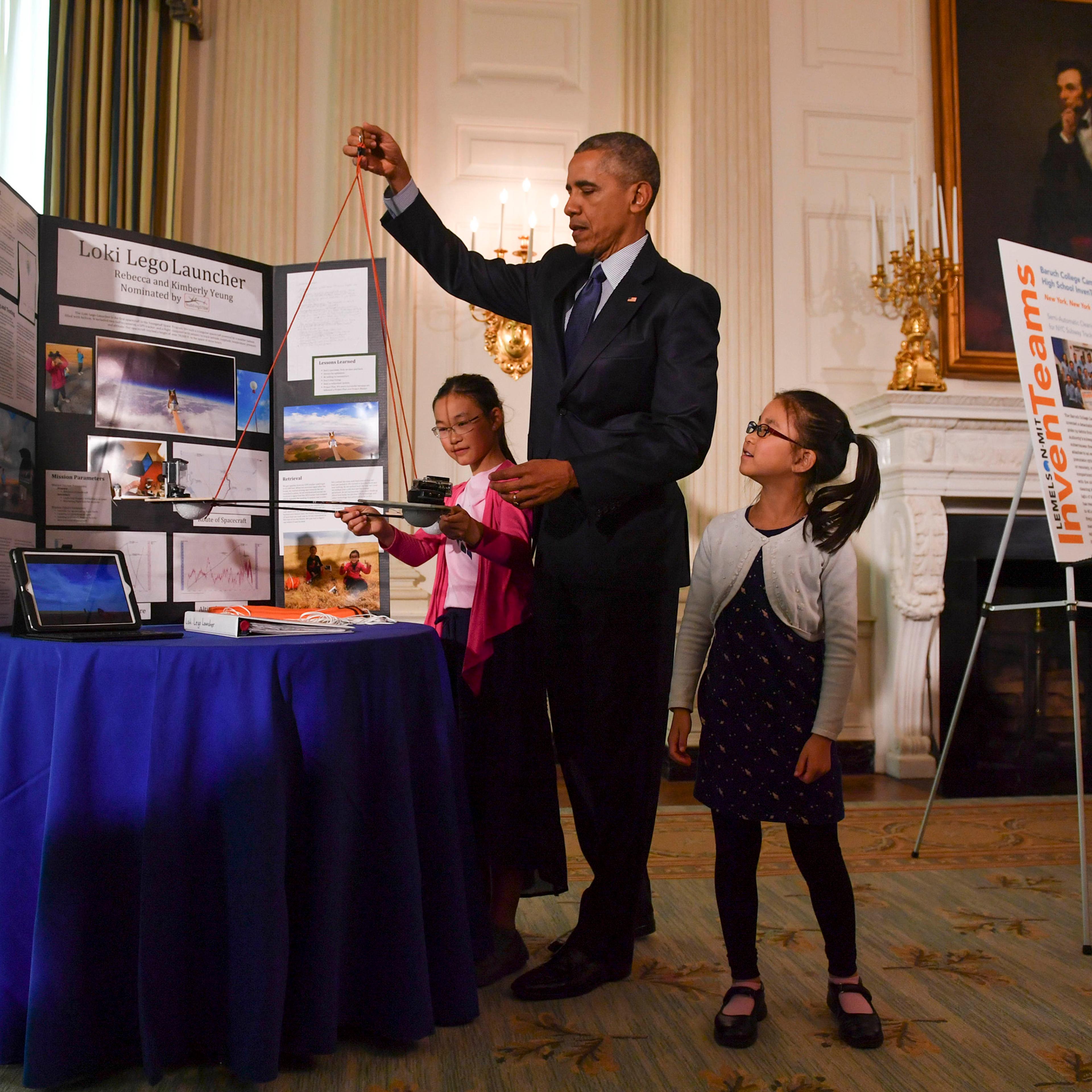 Sisters Kimberly, 9, right, and Rebecca Yeung, 11, of Seattle, WA., look on as President Barack Obama lifts their spacecraft science fair project during the sixth and final, annual White House Science Fair at The White House in Washington on April 13, 20