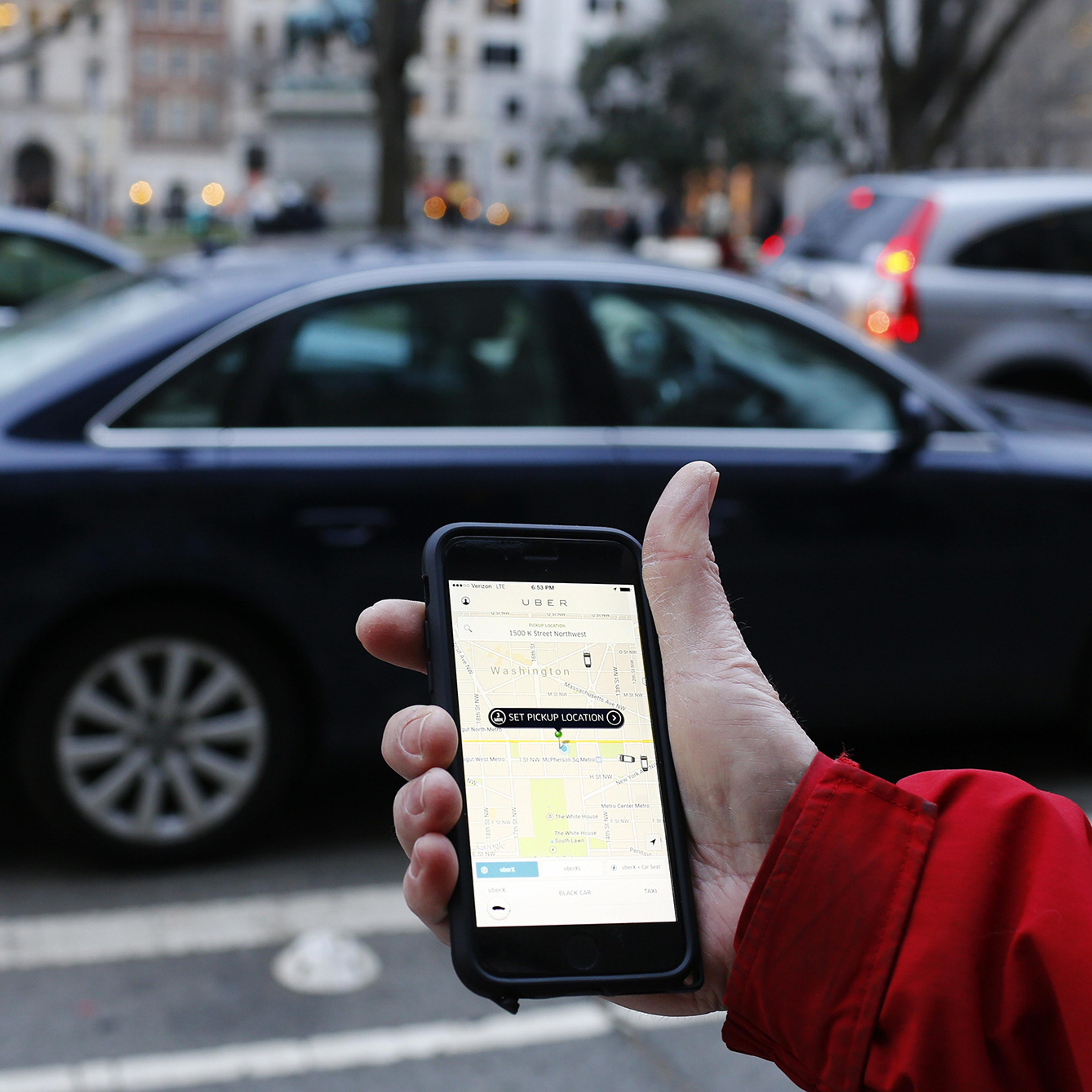 person using Uber app on mobile with car in background