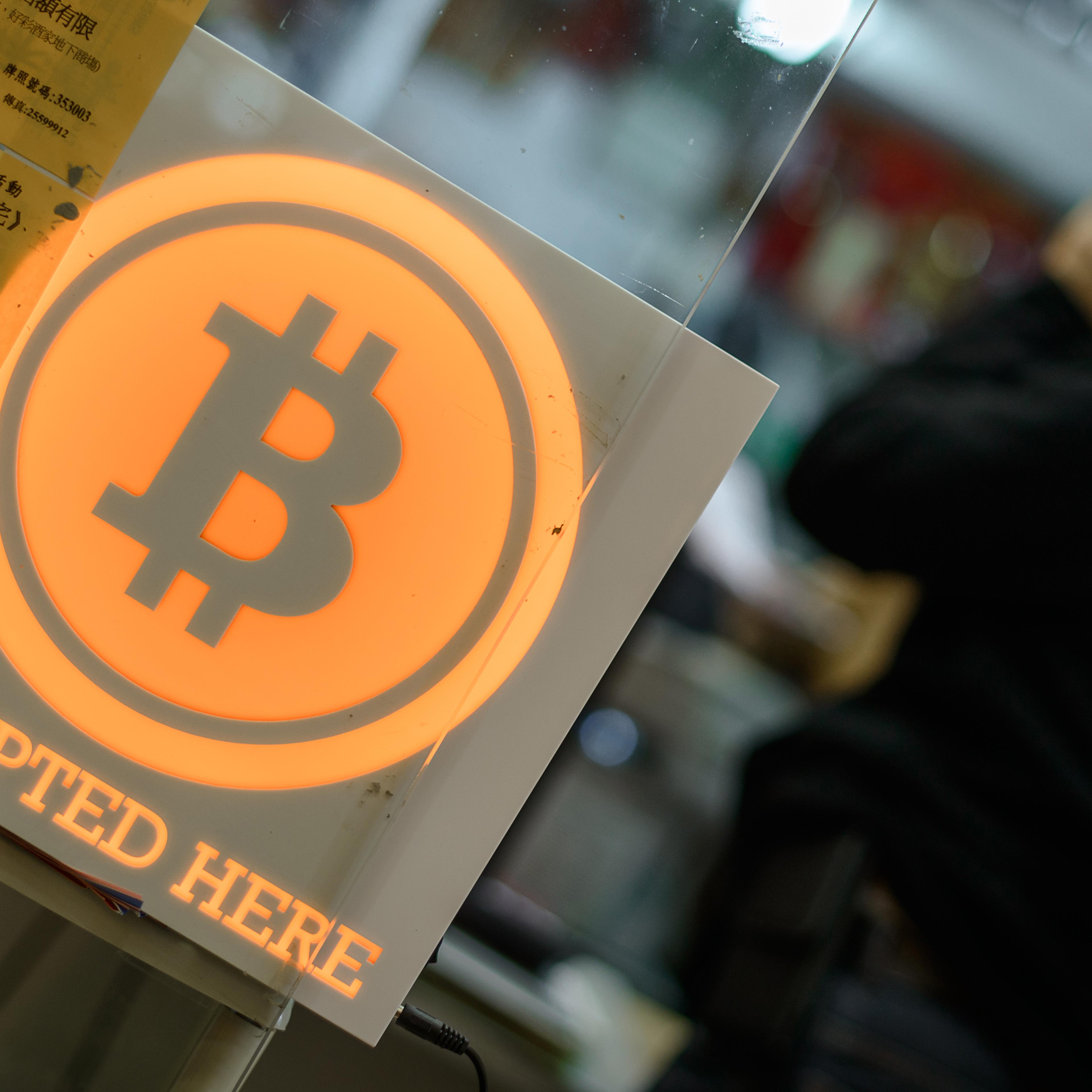 A man talks on a mobile phone in a shop displaying a bitcoin sign during the opening ceremony of the first bitcoin retail shop in Hong Kong on Feb. 28, 2014.