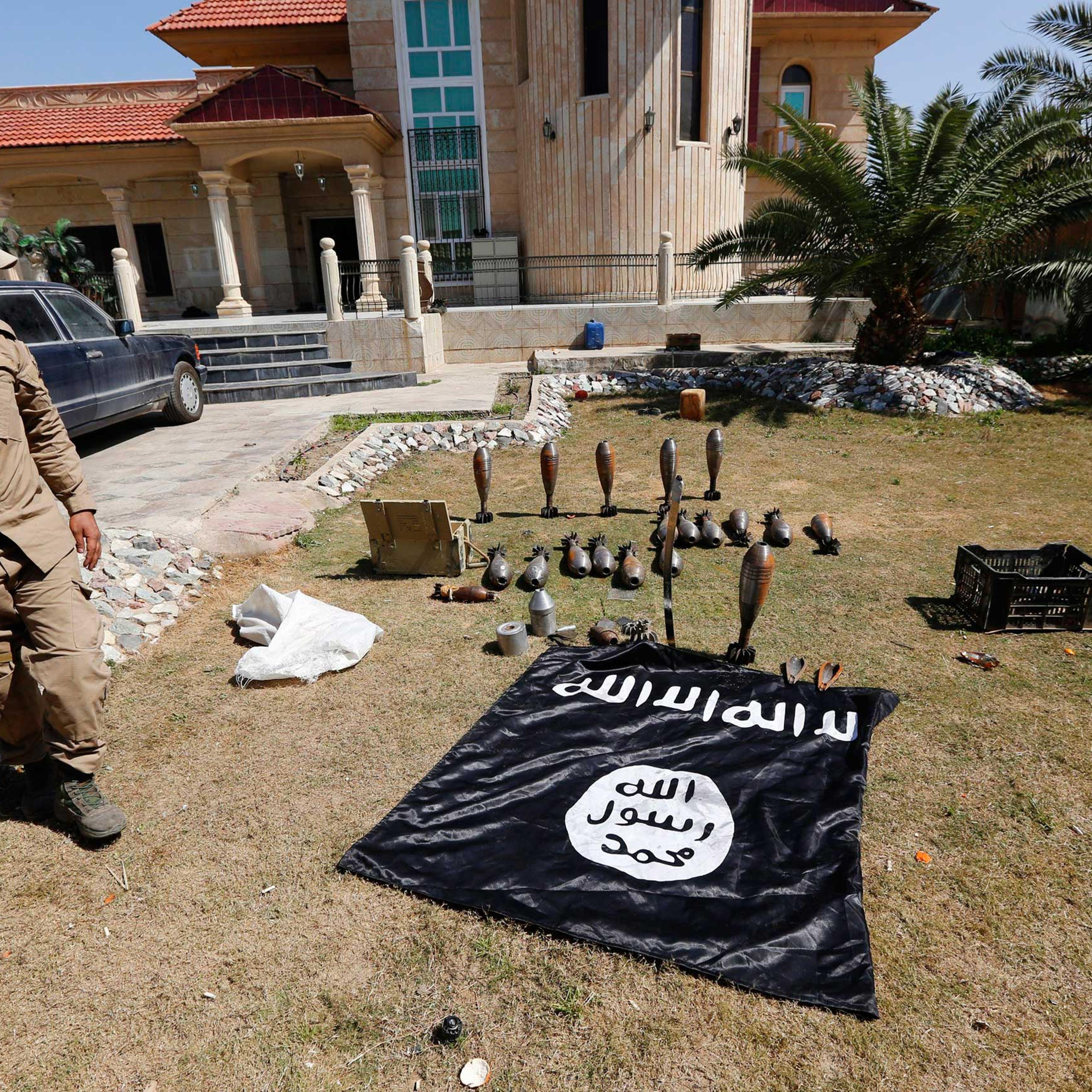 A Sunni fighter who has joined Shi'ite militia groups known collectively as Hashid Shaabi (Popular Mobilization), allied with Iraqi forces against the Islamic State, looks at an Islamic State flag and ammunition displayed in al-Alam Salahuddin province,