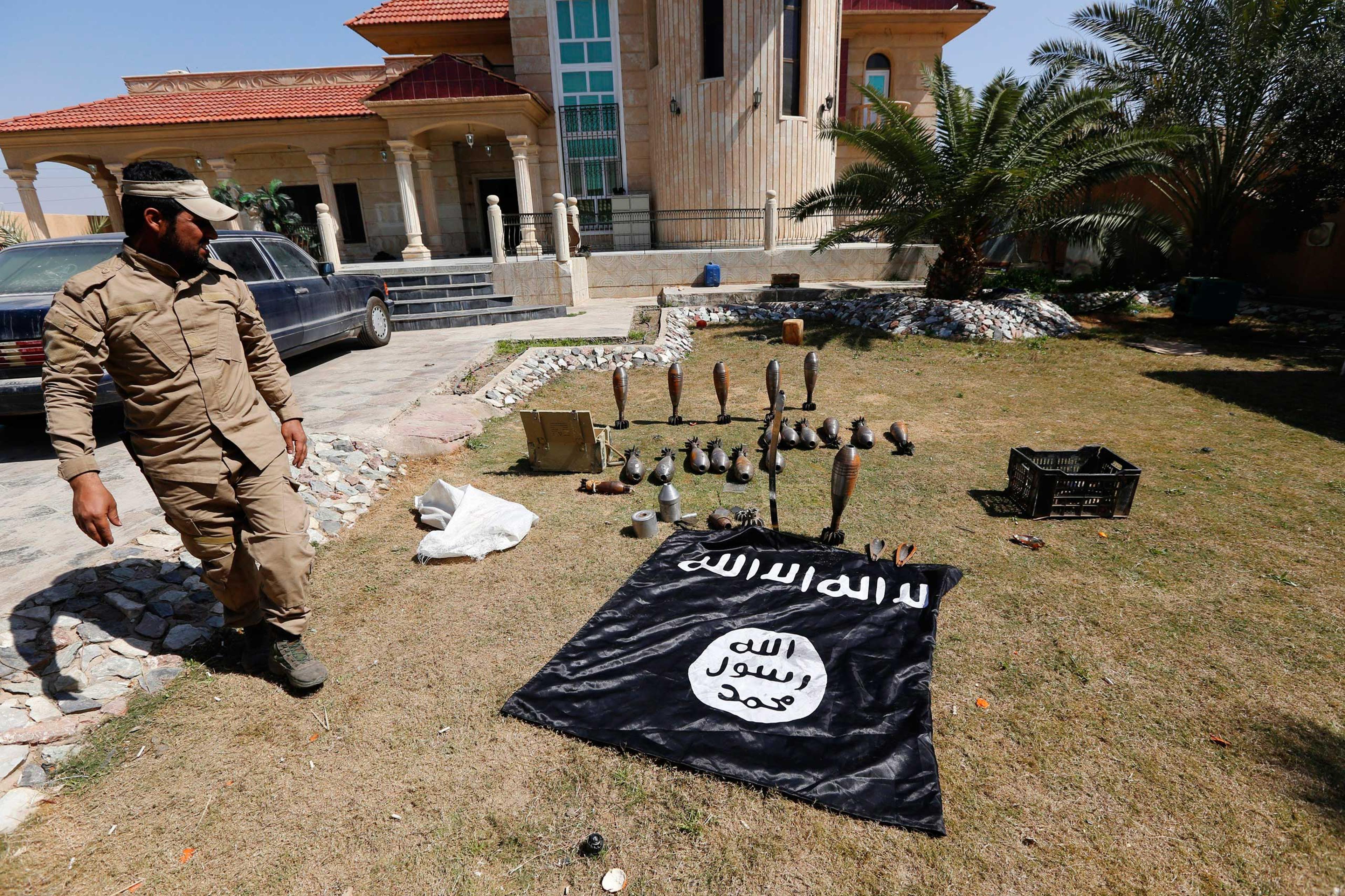 A Sunni fighter who has joined Shi'ite militia groups known collectively as Hashid Shaabi (Popular Mobilization), allied with Iraqi forces against the Islamic State, looks at an Islamic State flag and ammunition displayed in al-Alam Salahuddin province,