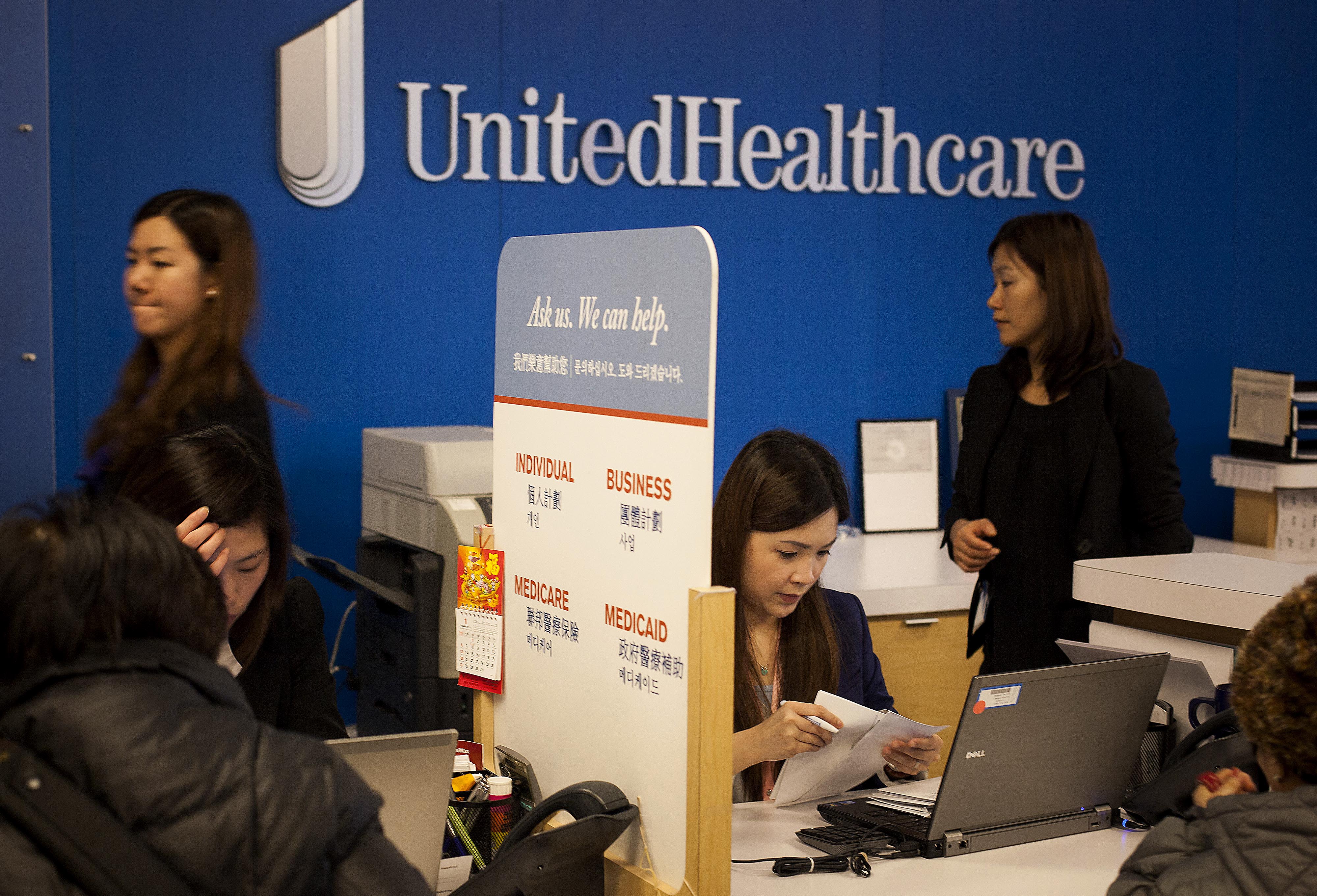 Representatives speak with customers at a UnitedHealthcare store in the Queens borough of New York, U.S., on Monday, Jan. 14, 2013.