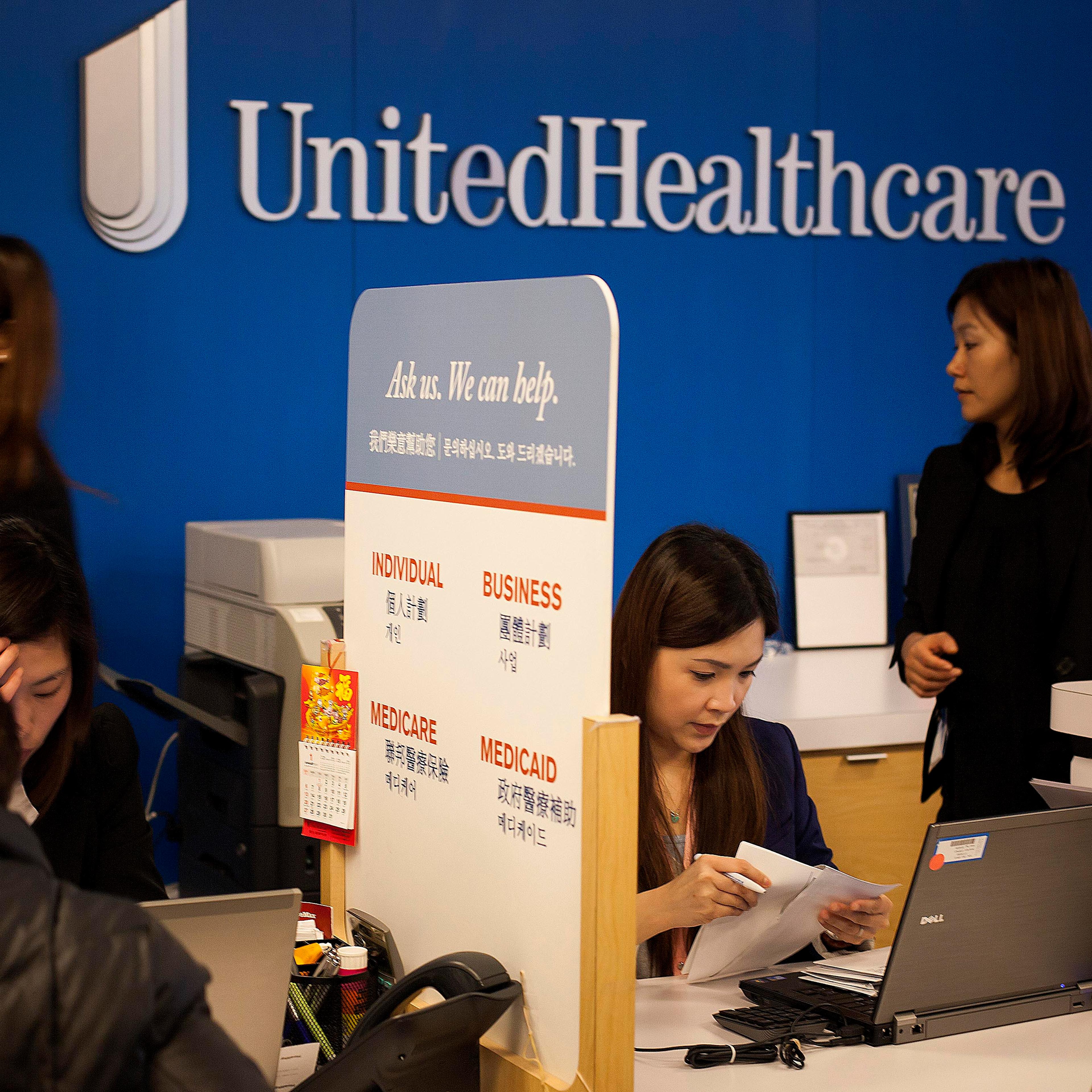 Representatives speak with customers at a UnitedHealthcare store in the Queens borough of New York, U.S., on Monday, Jan. 14, 2013.