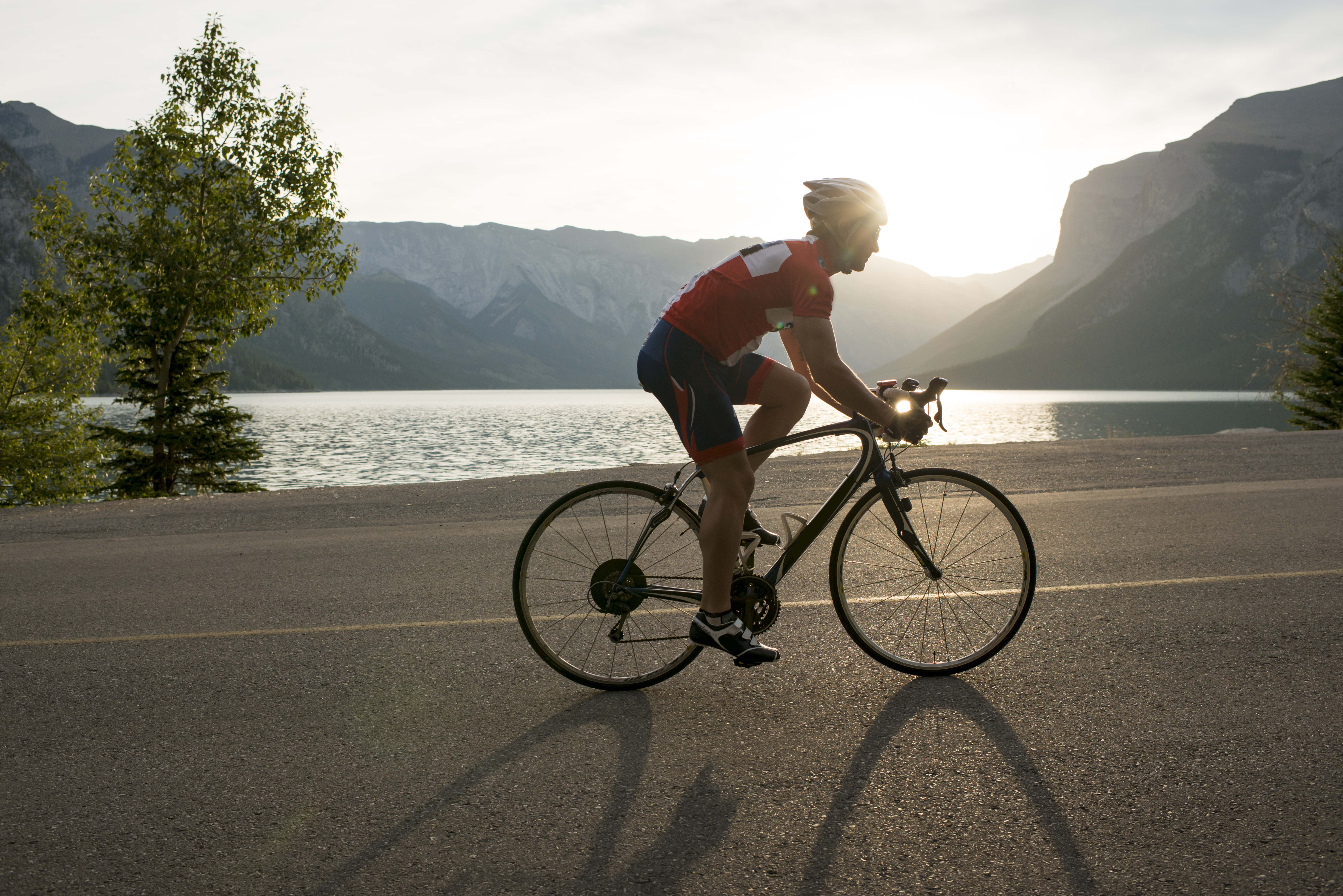 Road biker follows mountain road, sunrise