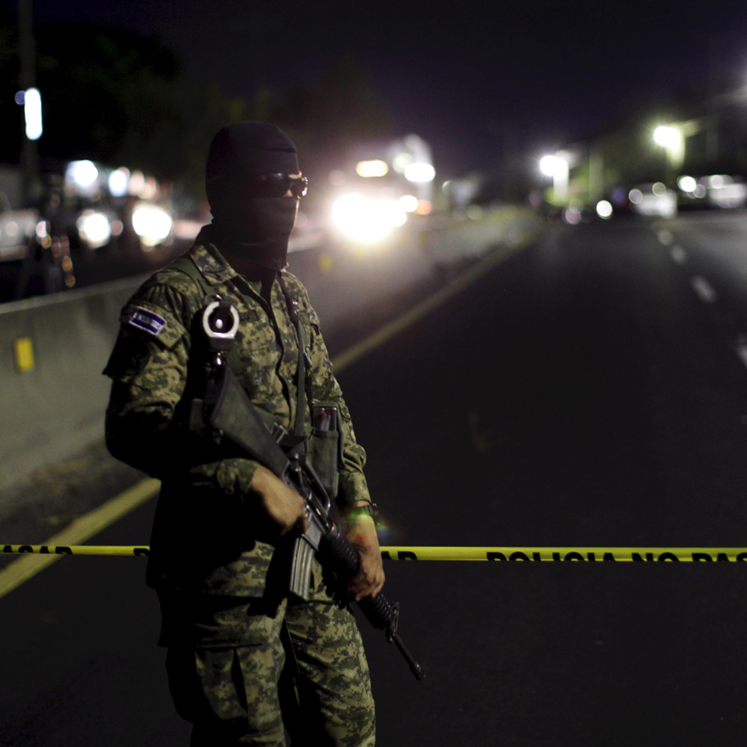 An army soldier guards a crime scene after eight people were shot dead in Quezaltepeque