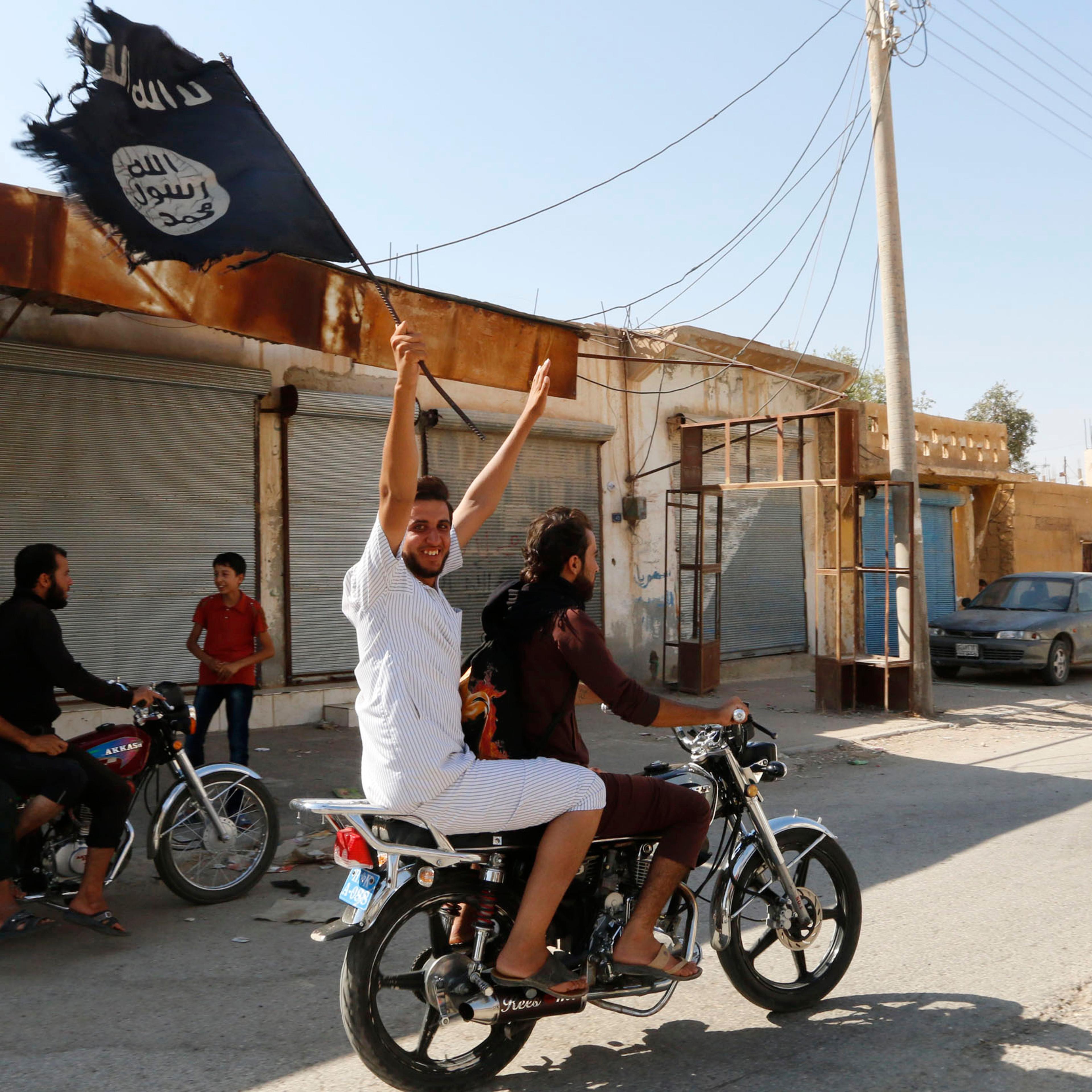 Resident of Tabqa city touring the streets on a motorcycle waves Islamist flag in celebration after Islamic State militants took over Tabqa air base, in nearby Raqqa city