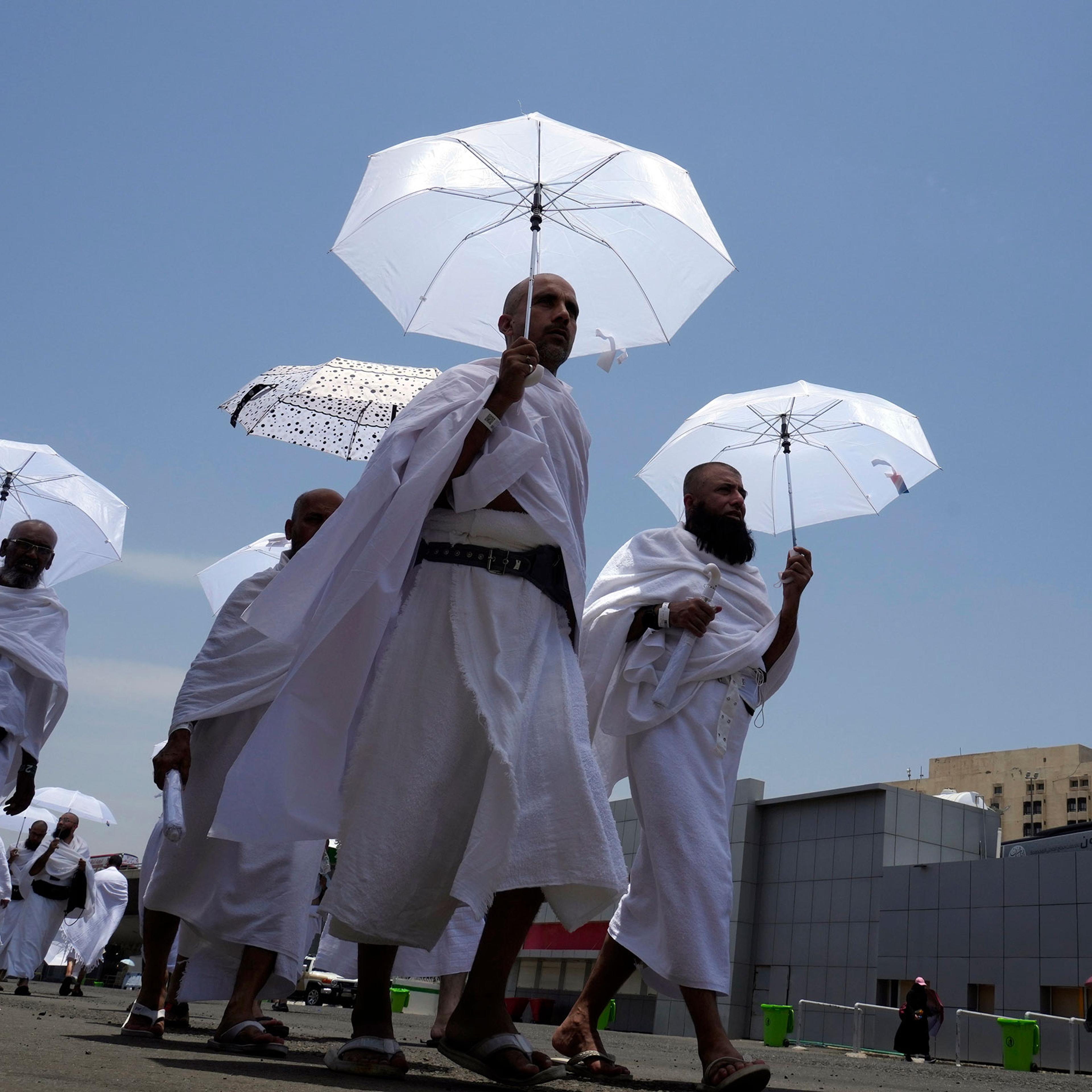 Muslim pilgrims walk, holding their umbrellas at the Mina tent camp in Mecca
