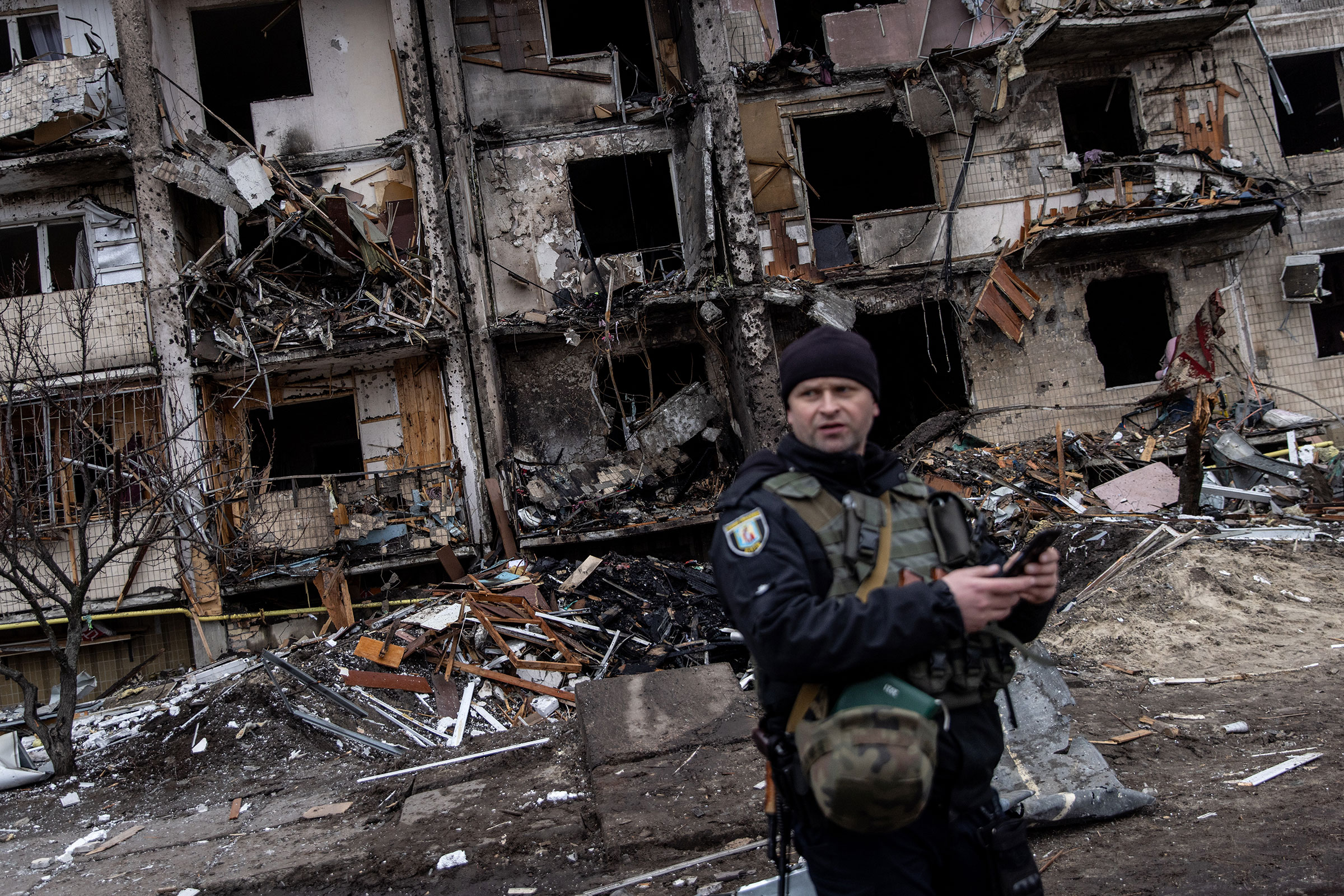 A Ukrainian police officer stands in front of a damaged residential block hit by an early morning missile strike in Kyiv, Ukraine on Feb. 25, 2022.
