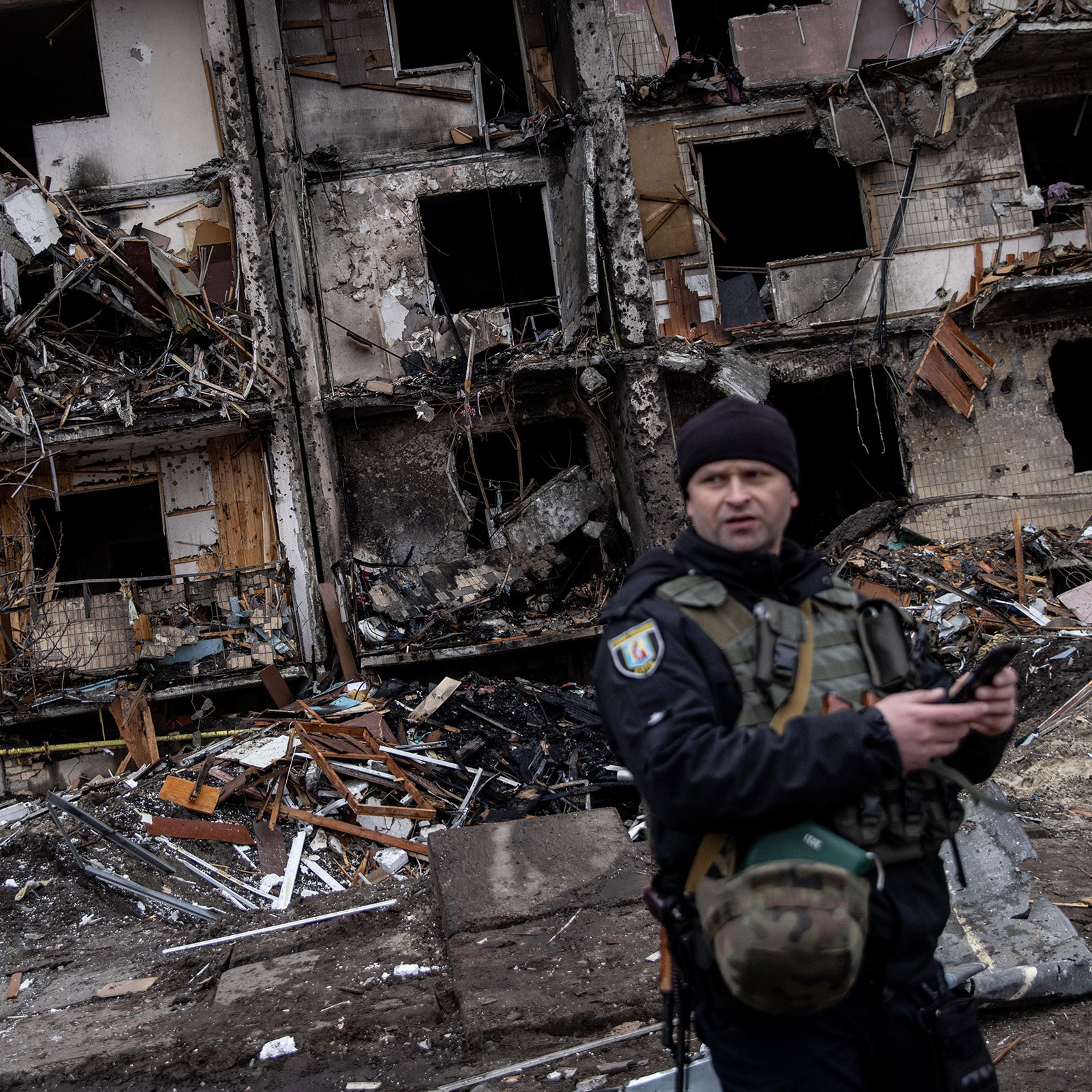 A Ukrainian police officer stands in front of a damaged residential block hit by an early morning missile strike in Kyiv, Ukraine on Feb. 25, 2022.