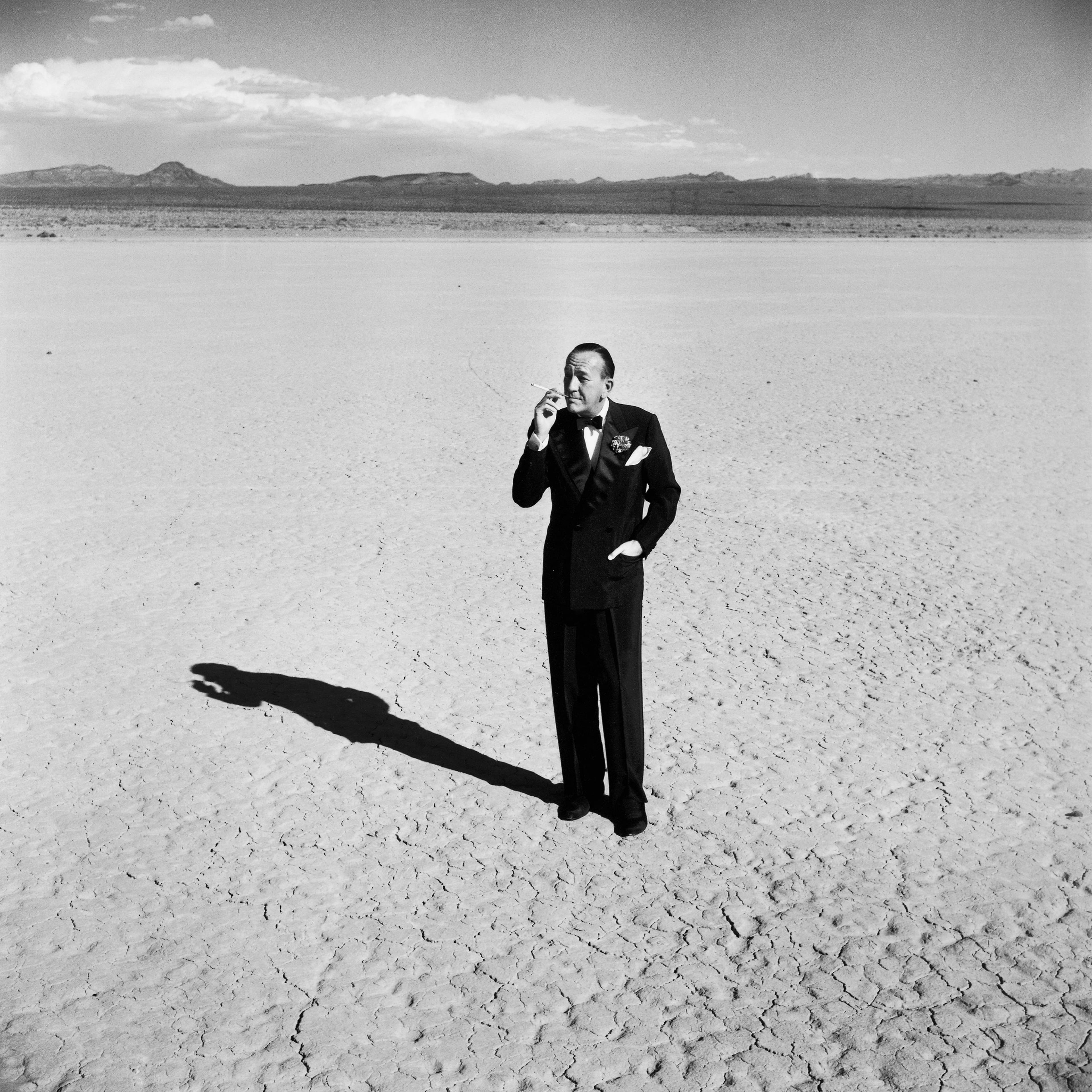 Noël Coward standing in a dry lake bed, Nevada, 1955.