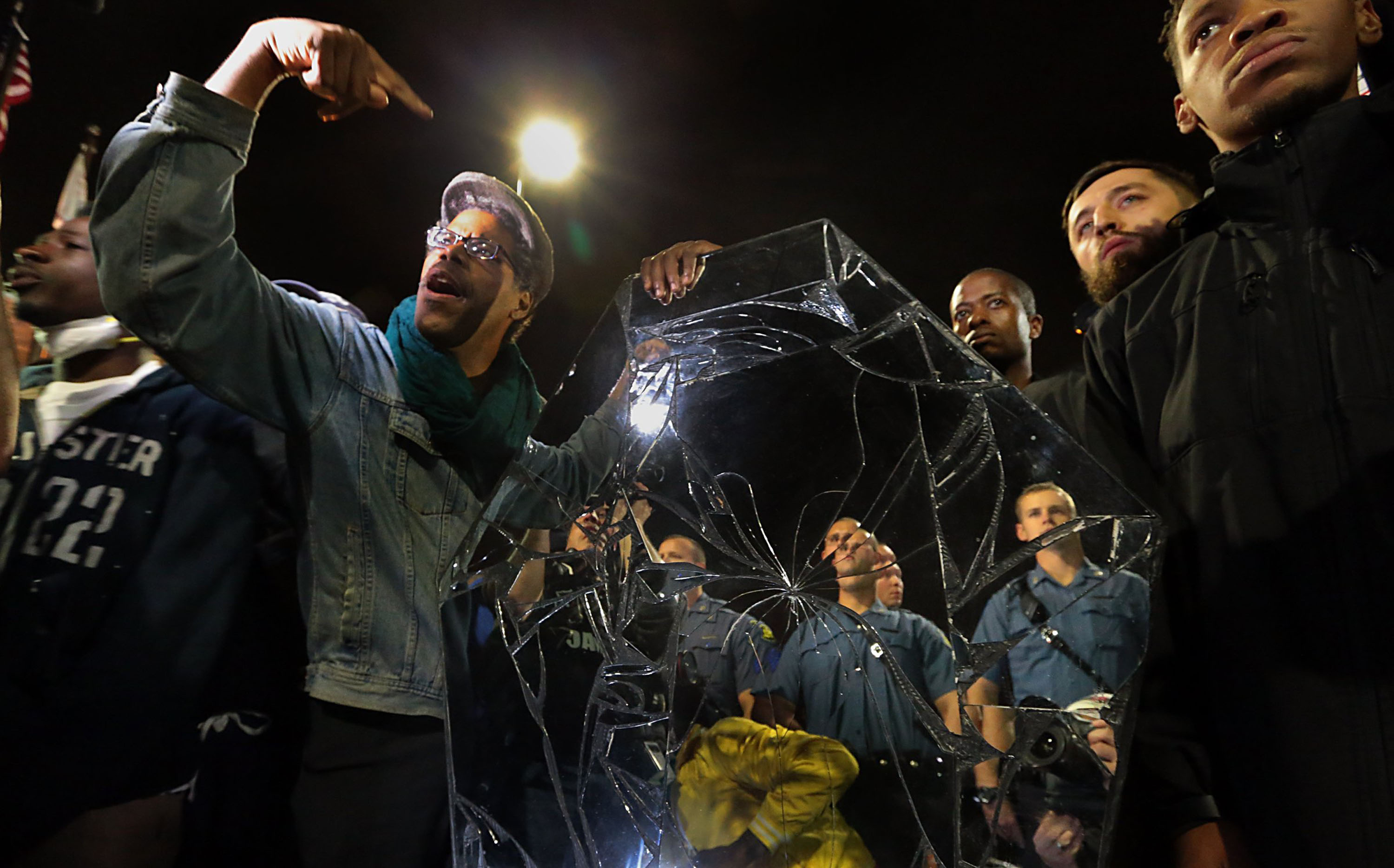 Protesters drop a mirrored casket in front of a line of police officers in front of the Ferguson Police Department in Ferguson, Mo. on Oct. 10, 2014.