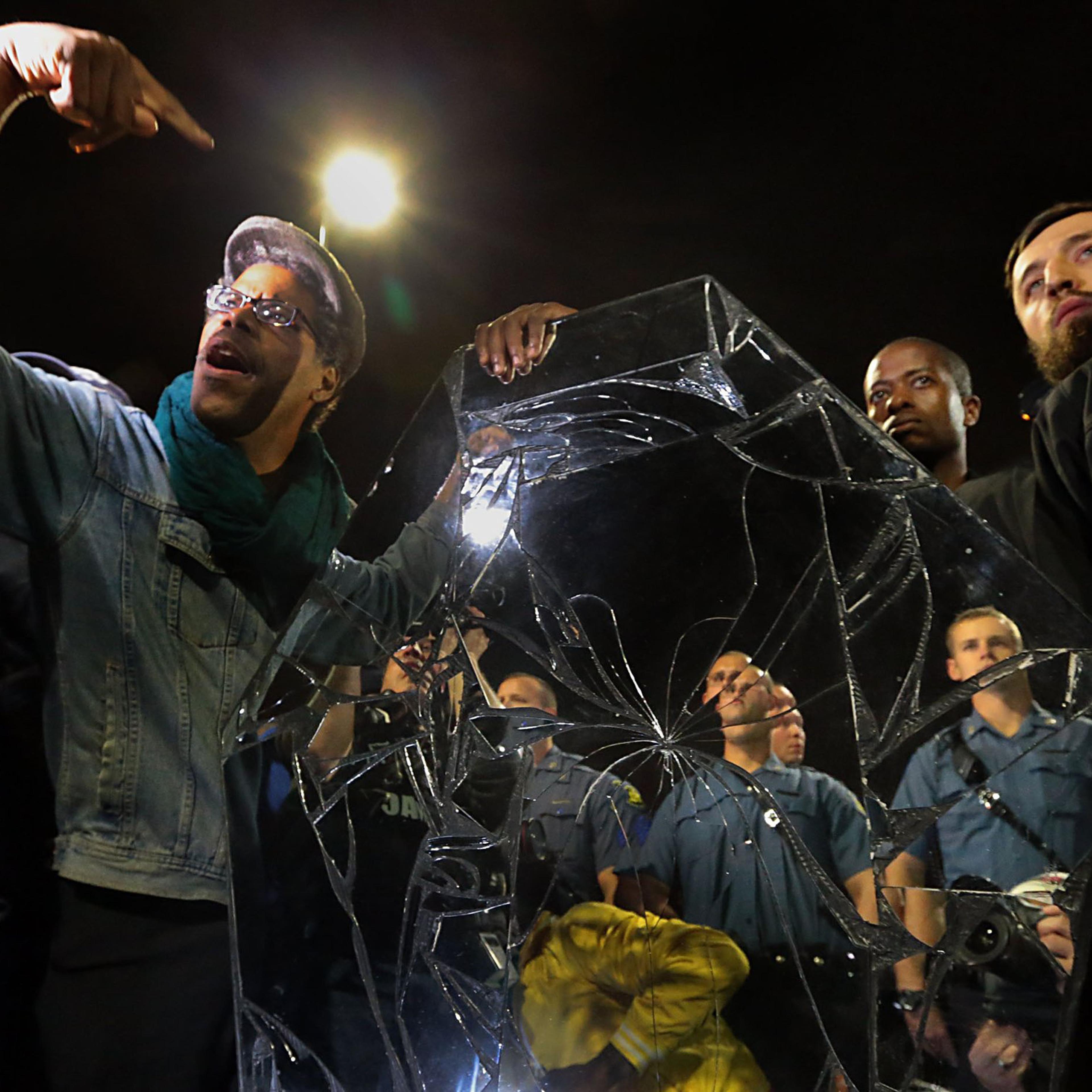 Protesters drop a mirrored casket in front of a line of police officers in front of the Ferguson Police Department in Ferguson, Mo. on Oct. 10, 2014.