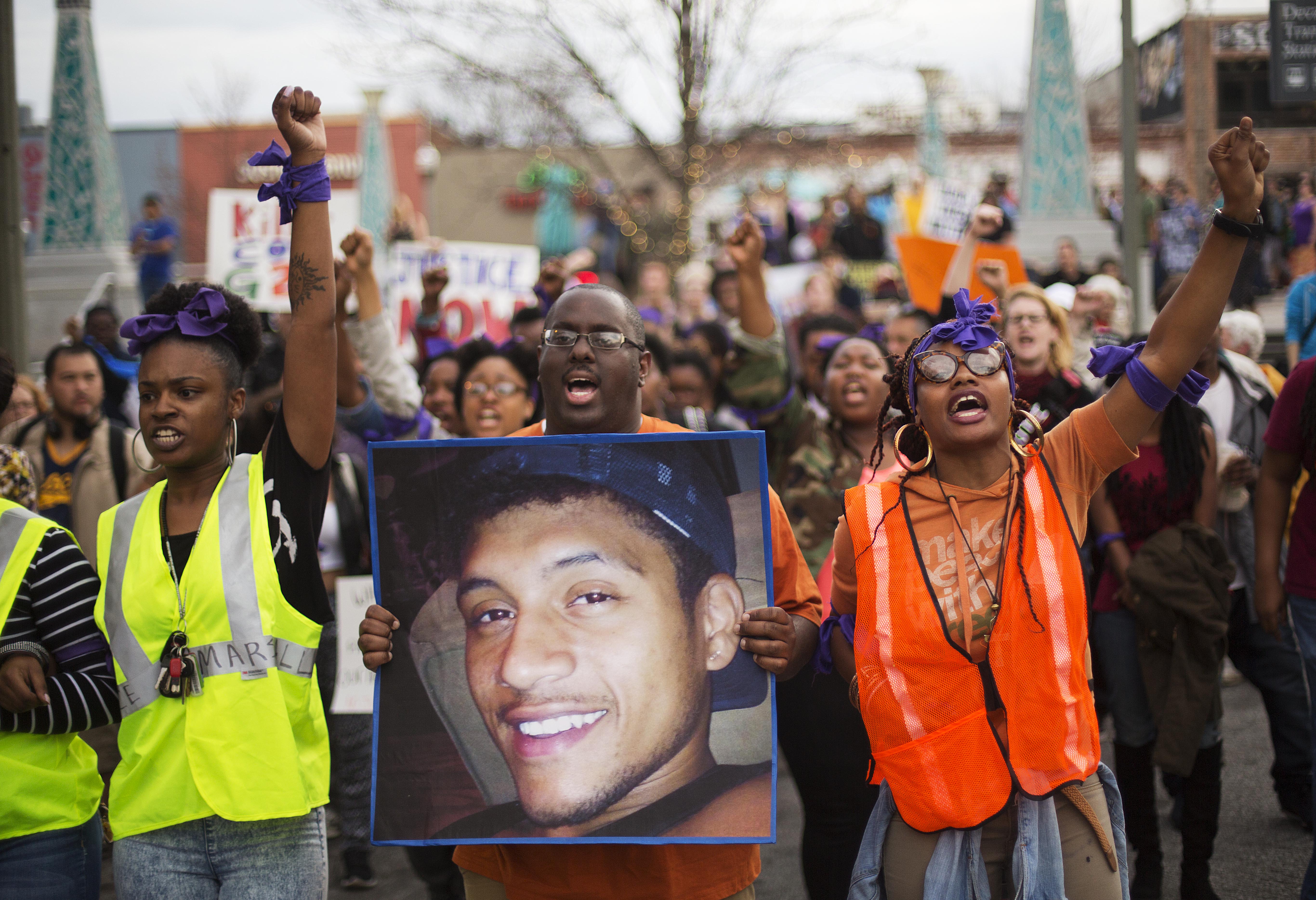Protesters carry a photo of Anthony Hill while marching through the street demonstrating Hill's shooting death by a police officer in Decatur, Ga. on March 11, 2015.