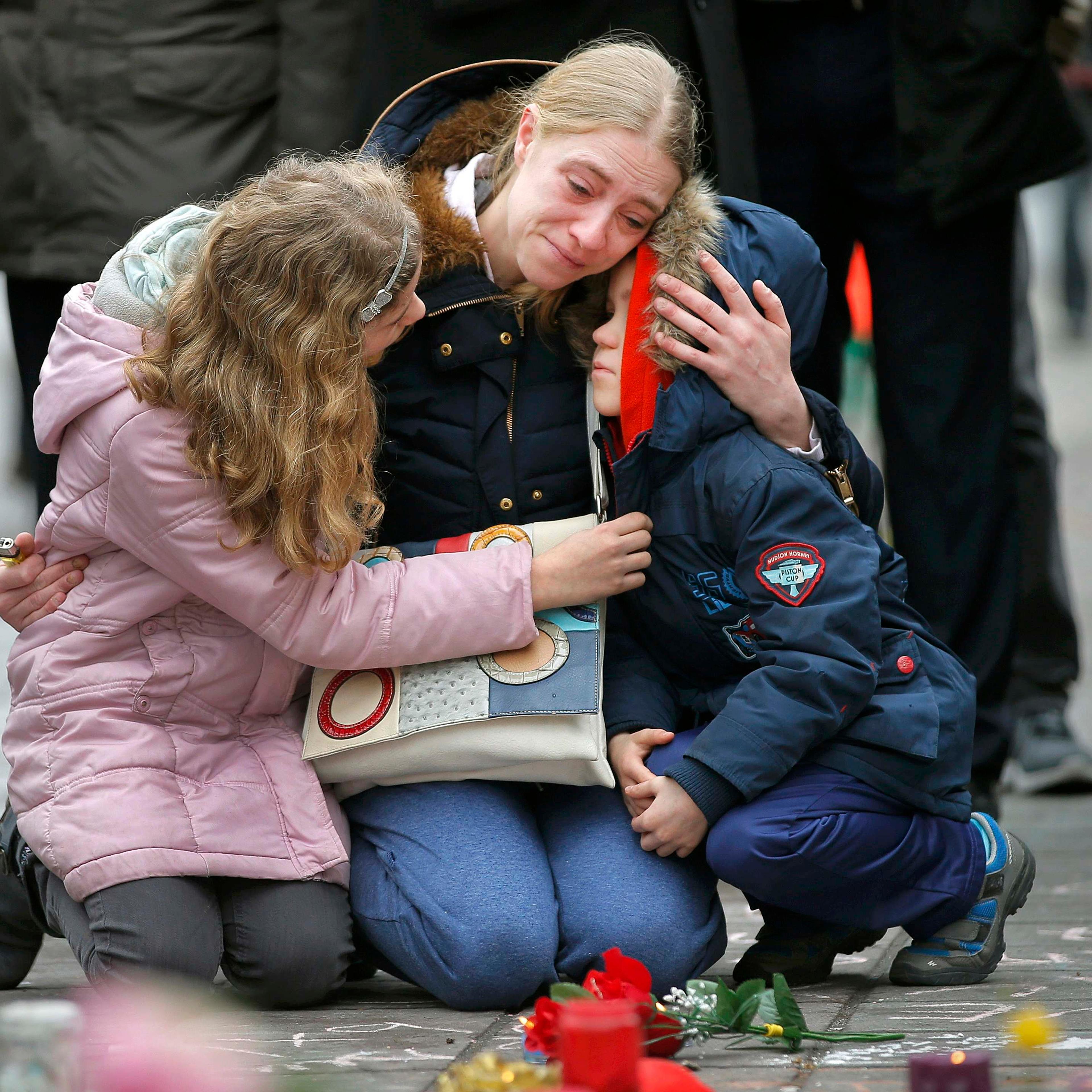 A woman consoles her children at a street memorial following bomb attacks in Brussels, Belgium
