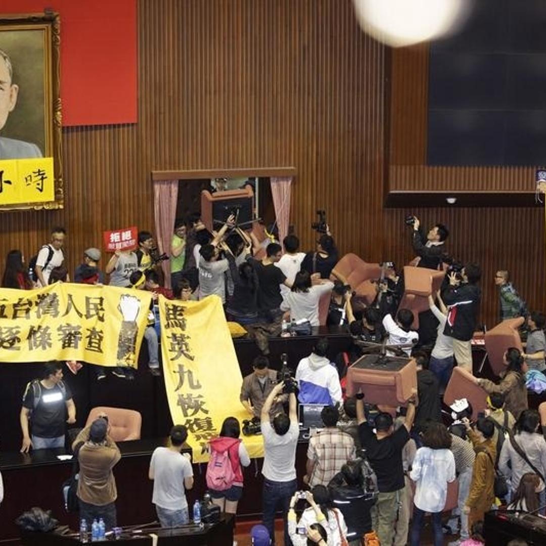 Students and protesters hold banners and chairs inside Taiwan's legislature in Taipei