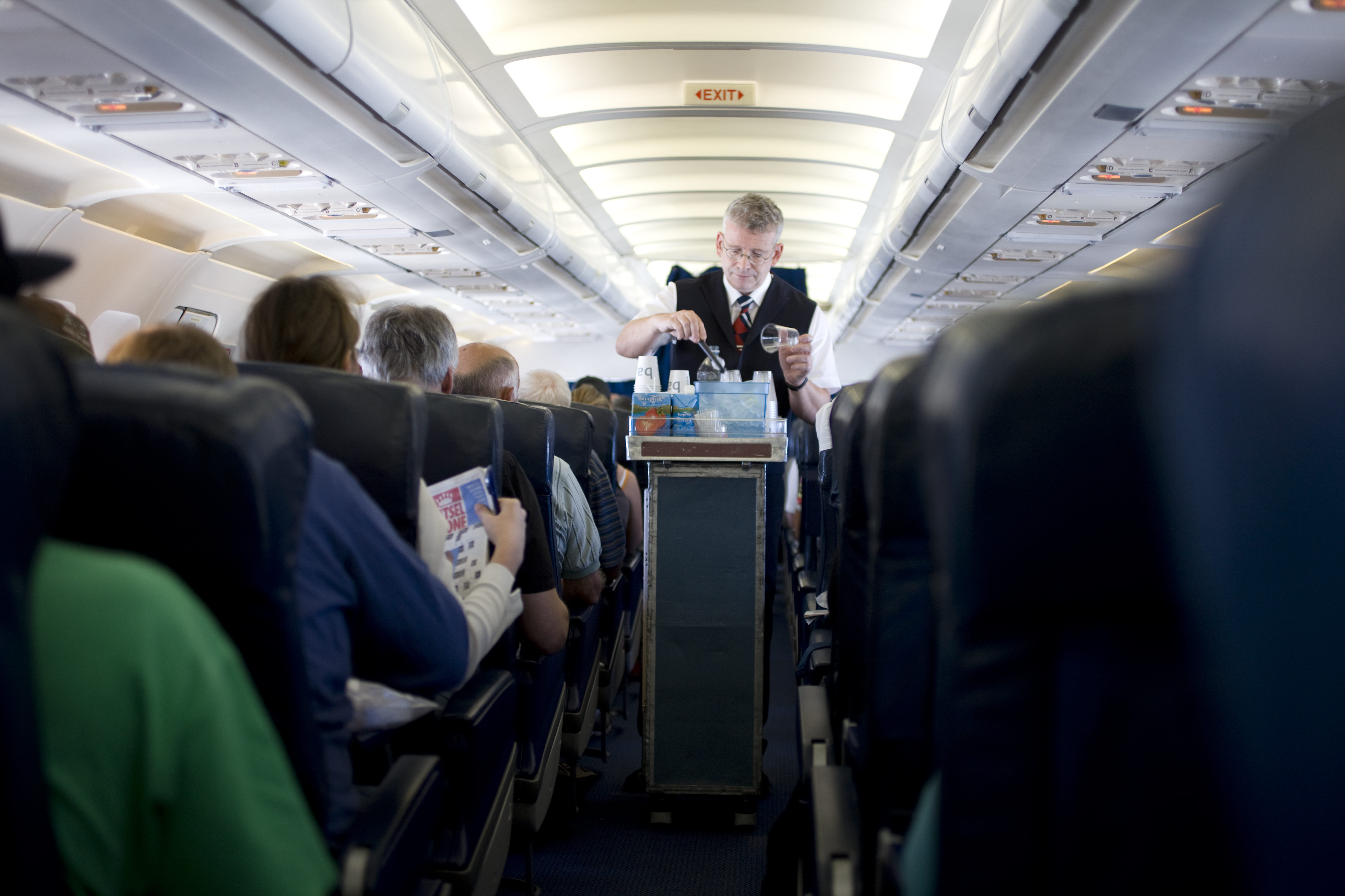 Interior of airplane showing air steward serving drinks