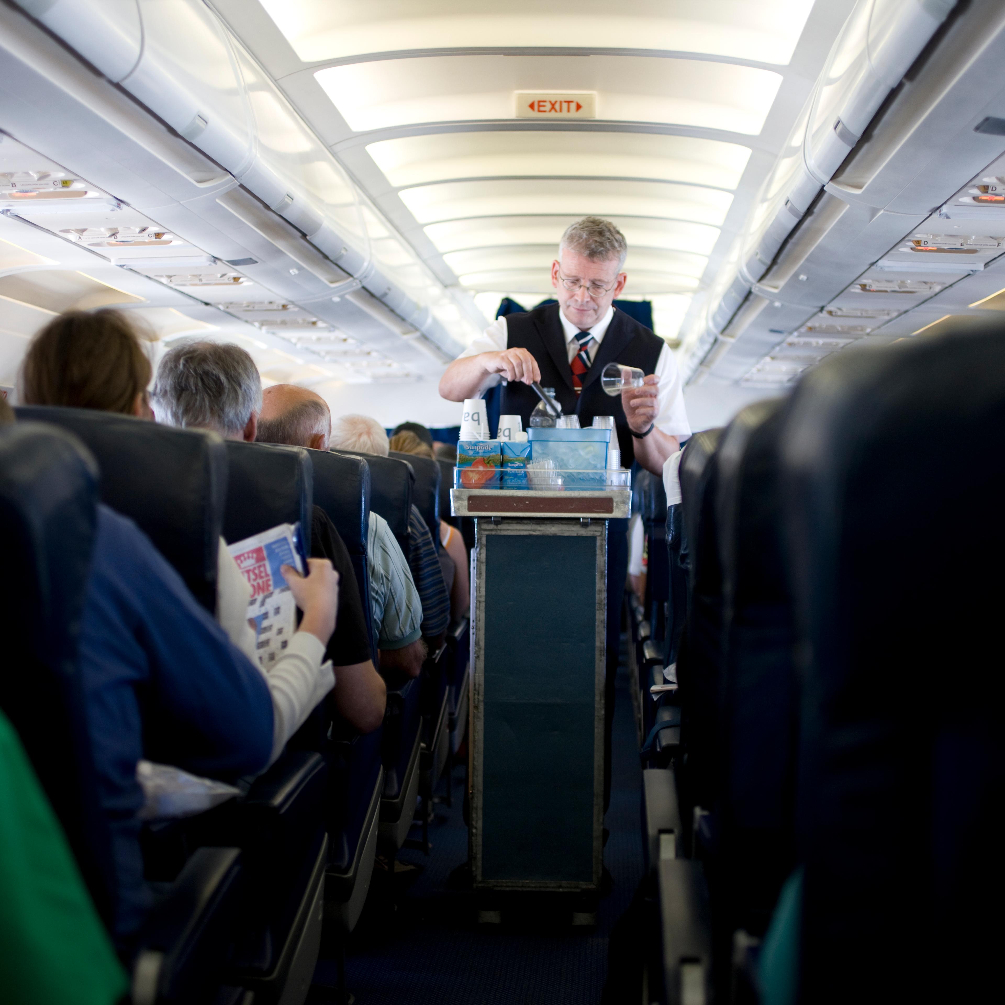 Interior of airplane showing air steward serving drinks