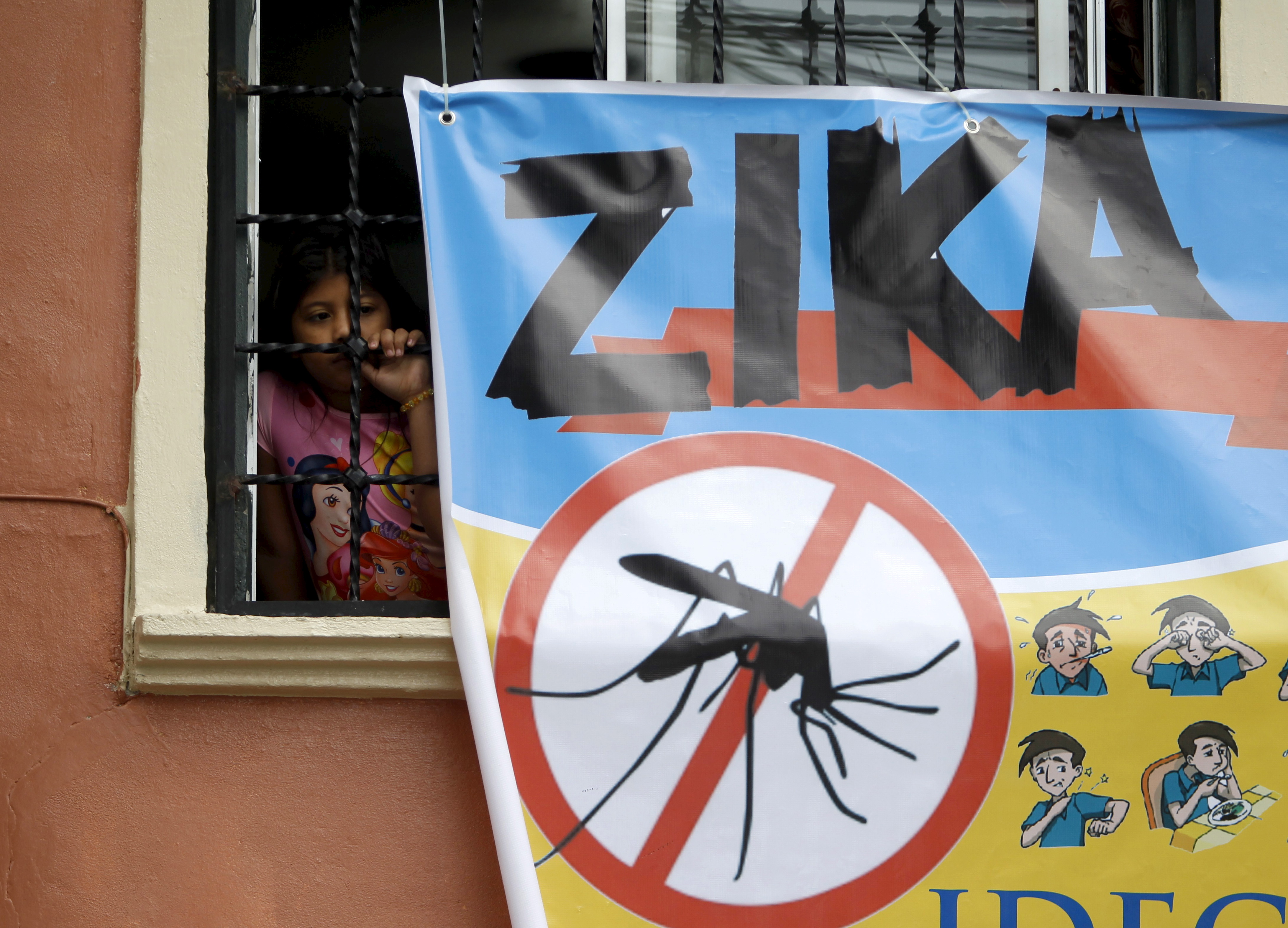 A woman looks on next to a banner as soldiers and municipal health workers take part in cleaning of the streets, gardens and homes as part of the city's efforts to prevent the spread of the Zika virus vector