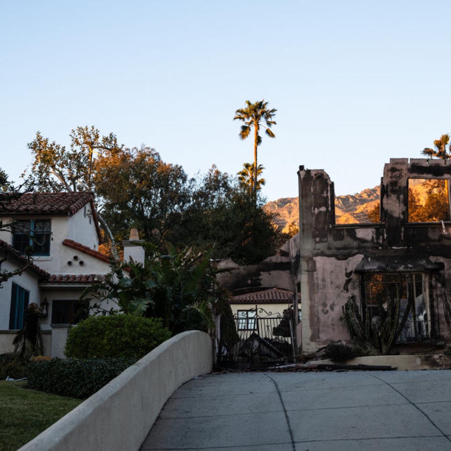 A home destroyed by the Eaton Fire is seen next to another left intact in Altadena, California