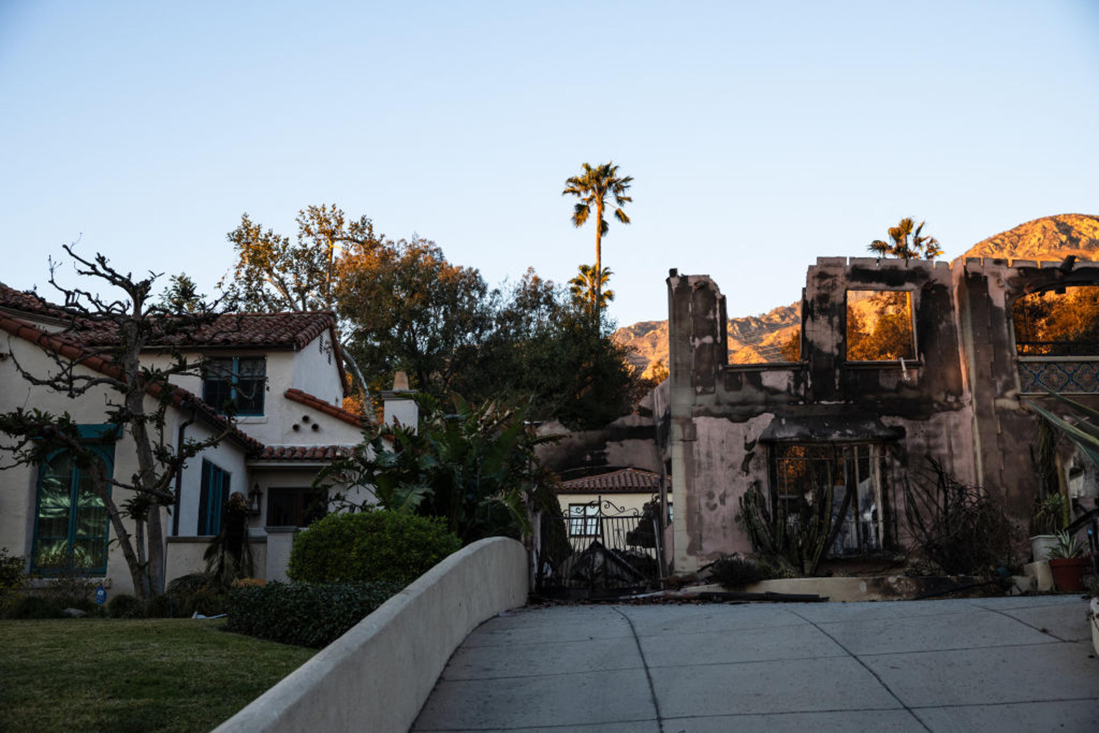 A home destroyed by the Eaton Fire is seen next to another left intact in Altadena, California