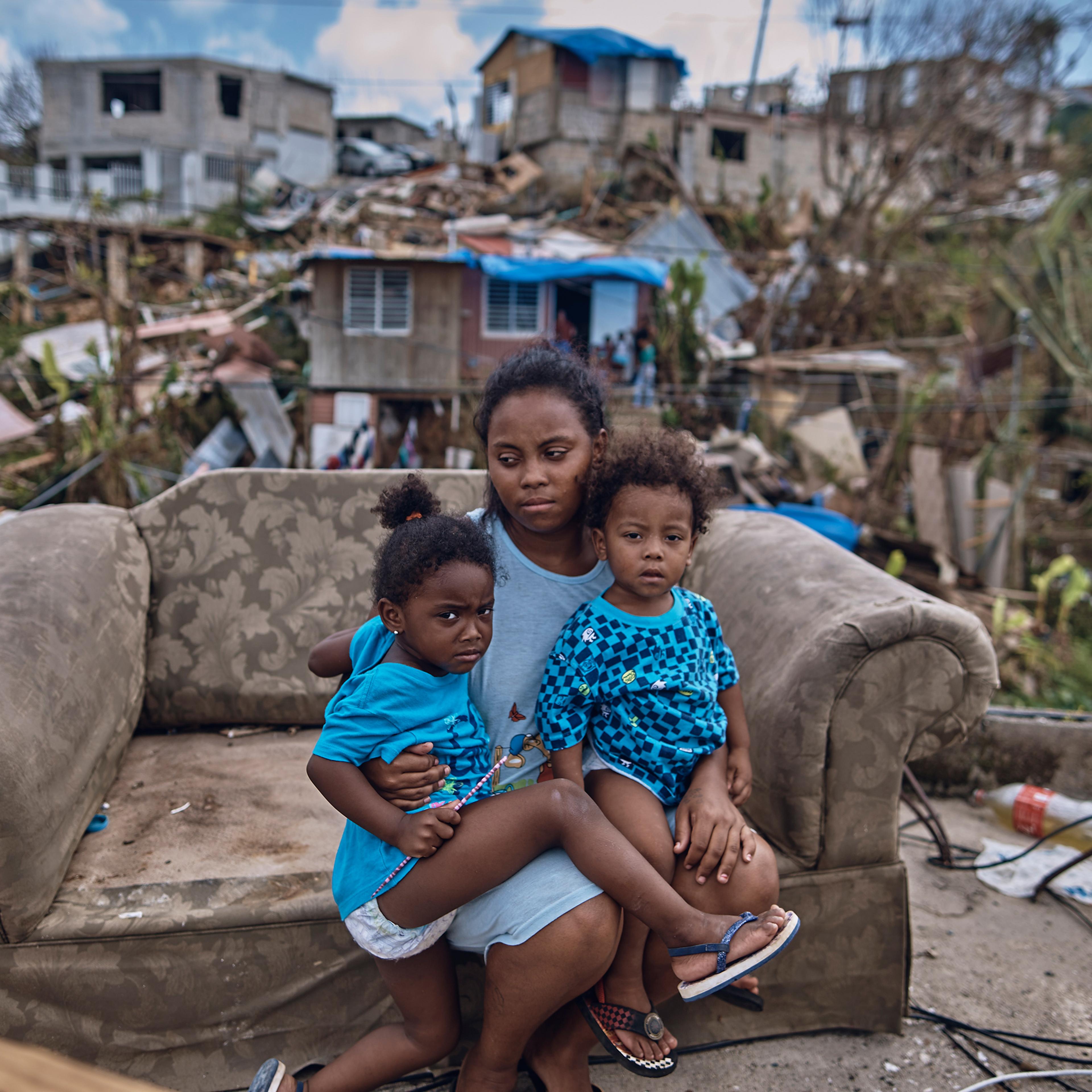 Darieliz Michelle Lopez, her 20-month-old son and three-year-old daughter sit for a portrait on the sofa where her apartment no longer stands in San Isidro, Puerto Rico, on Sept. 28, 2017.