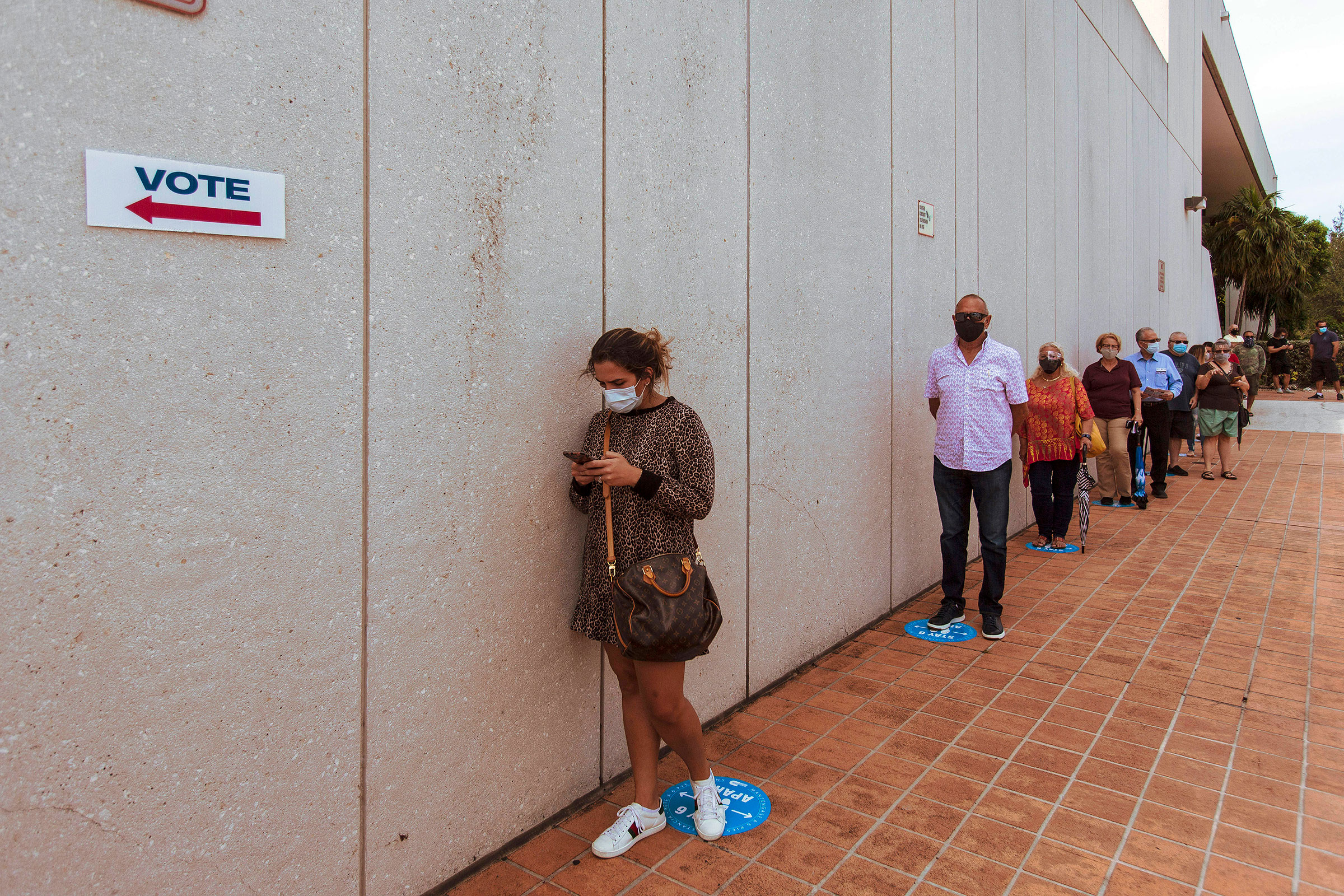 People wait on line to cast their ballot on the first day of early voting at a polling place in Miami, Fla., Oct. 19, 2020.