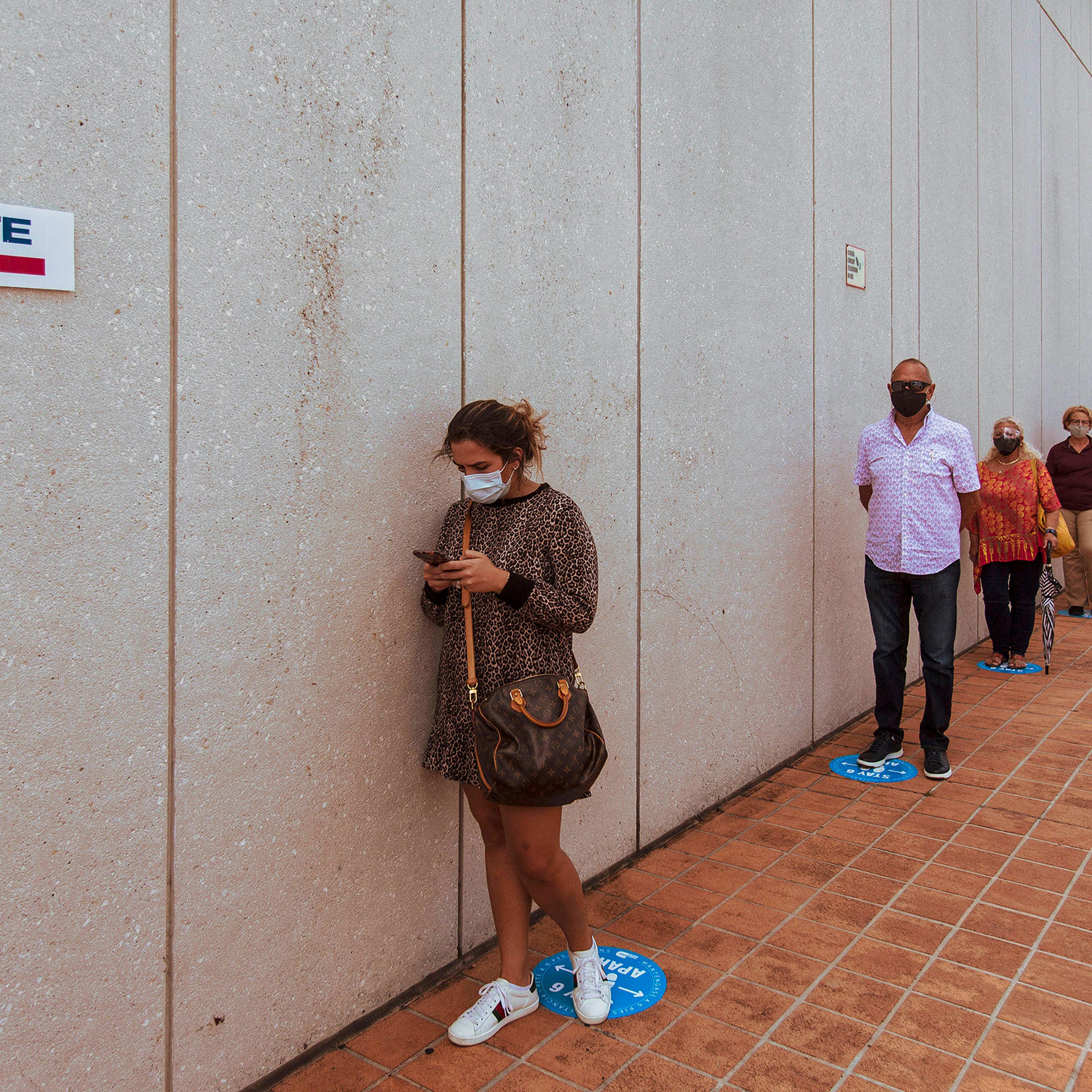 People wait on line to cast their ballot on the first day of early voting at a polling place in Miami, Fla., Oct. 19, 2020.