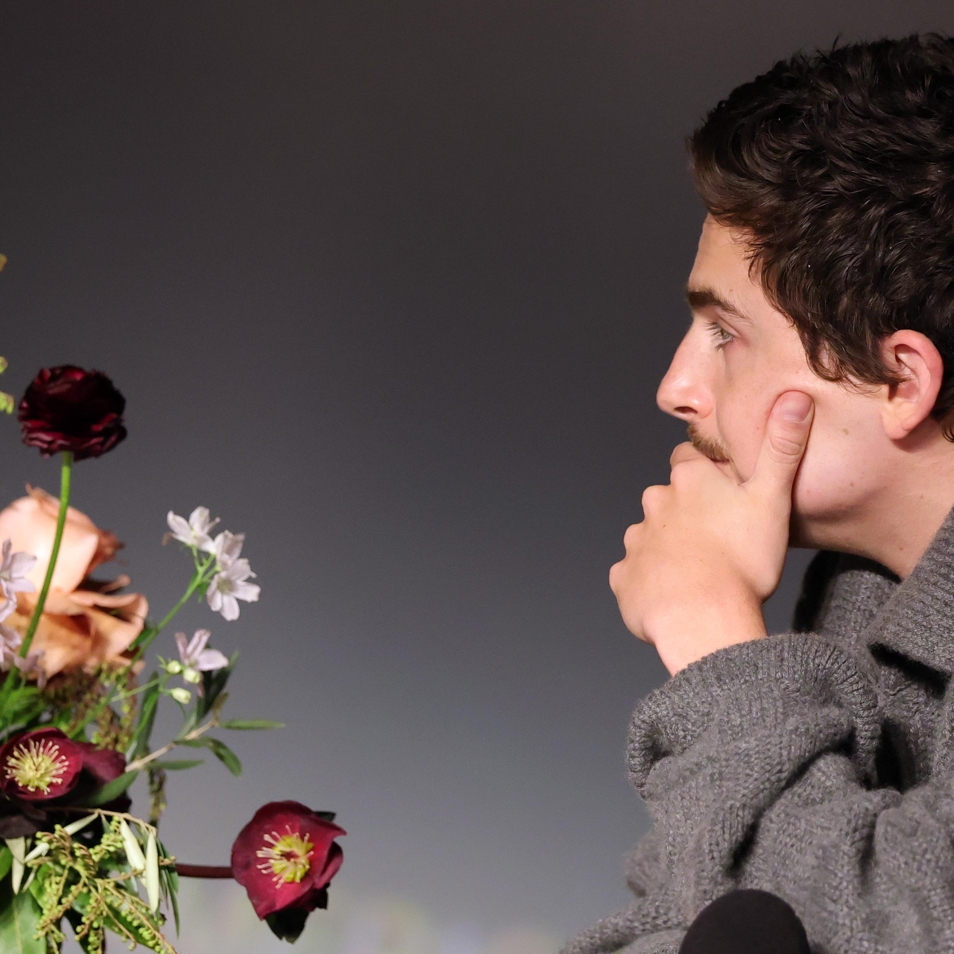 Timothée Chalamet ponders a bouquet of flowers.