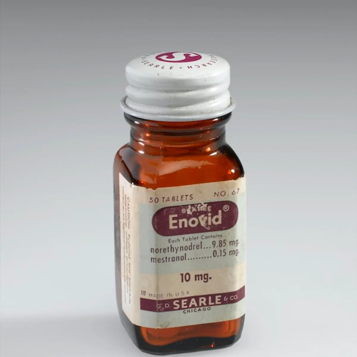 Bottle of Enovid tabs 10mg, early 1960s. Front three quarter view. Graduated grey background.