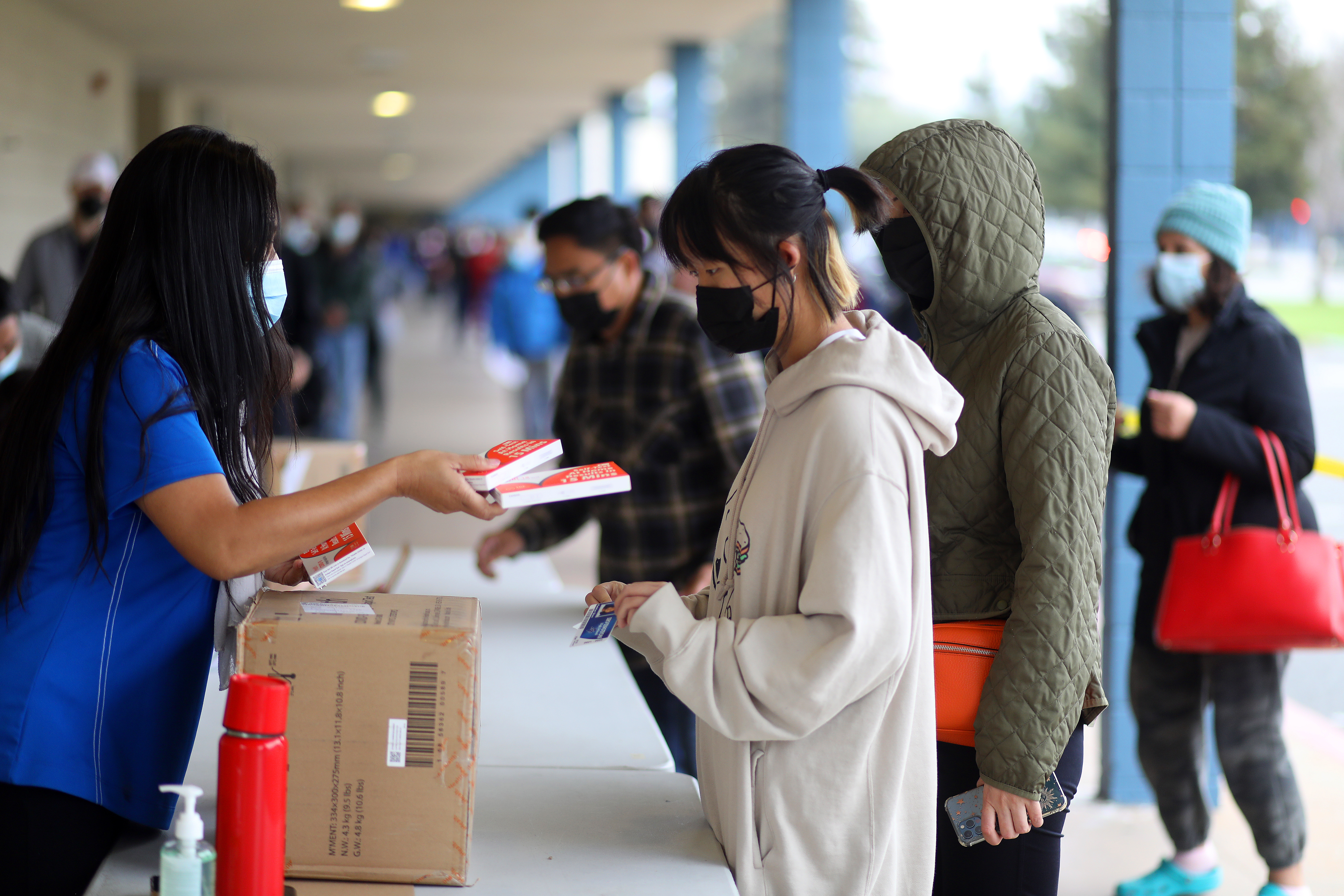 Fremont Unified School District staff members distribute COVID-19 rapid tests to students at Irvington High School on Thursday, Jan. 6, 2022, in Fremont, Calif.
