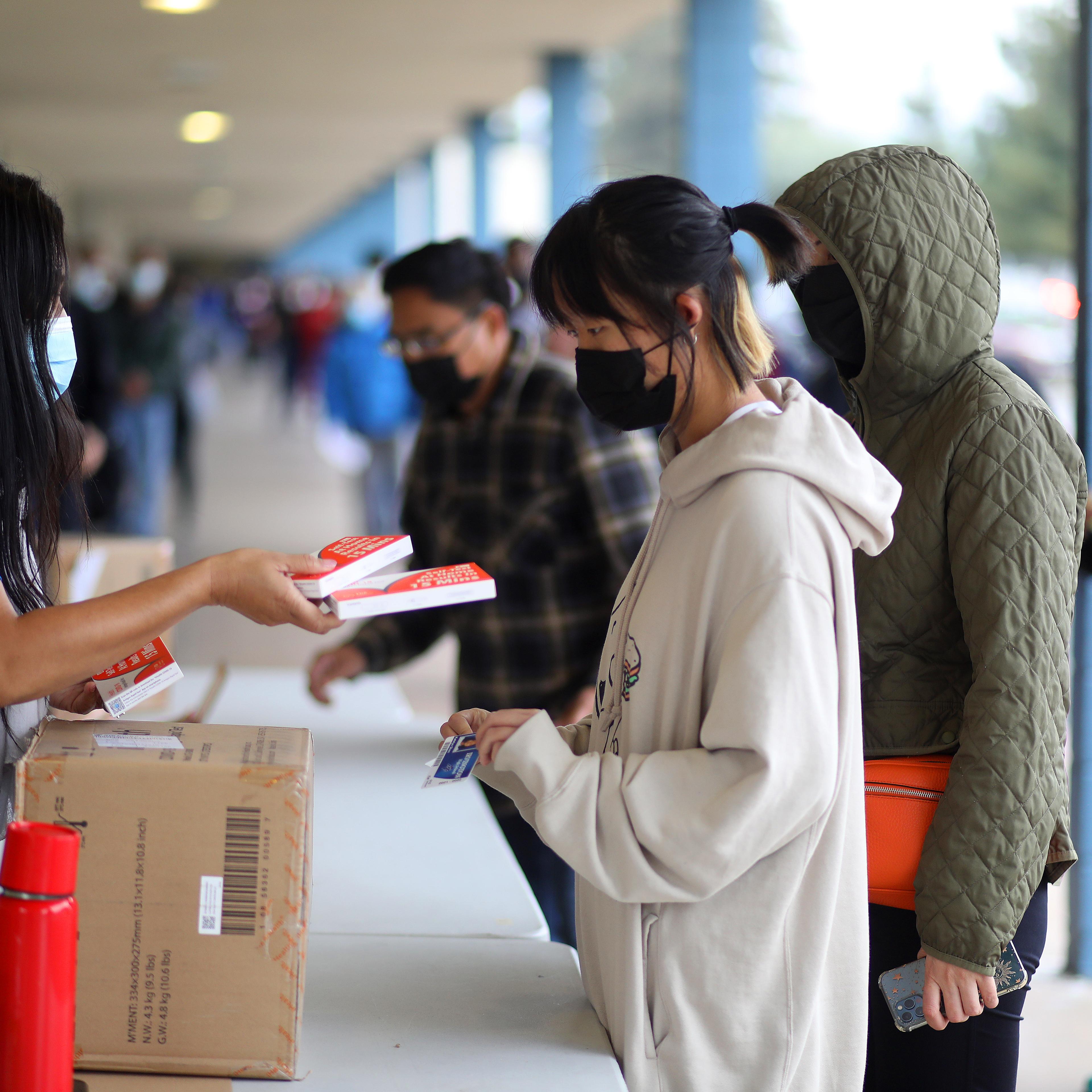 Fremont Unified School District staff members distribute COVID-19 rapid tests to students at Irvington High School on Thursday, Jan. 6, 2022, in Fremont, Calif.